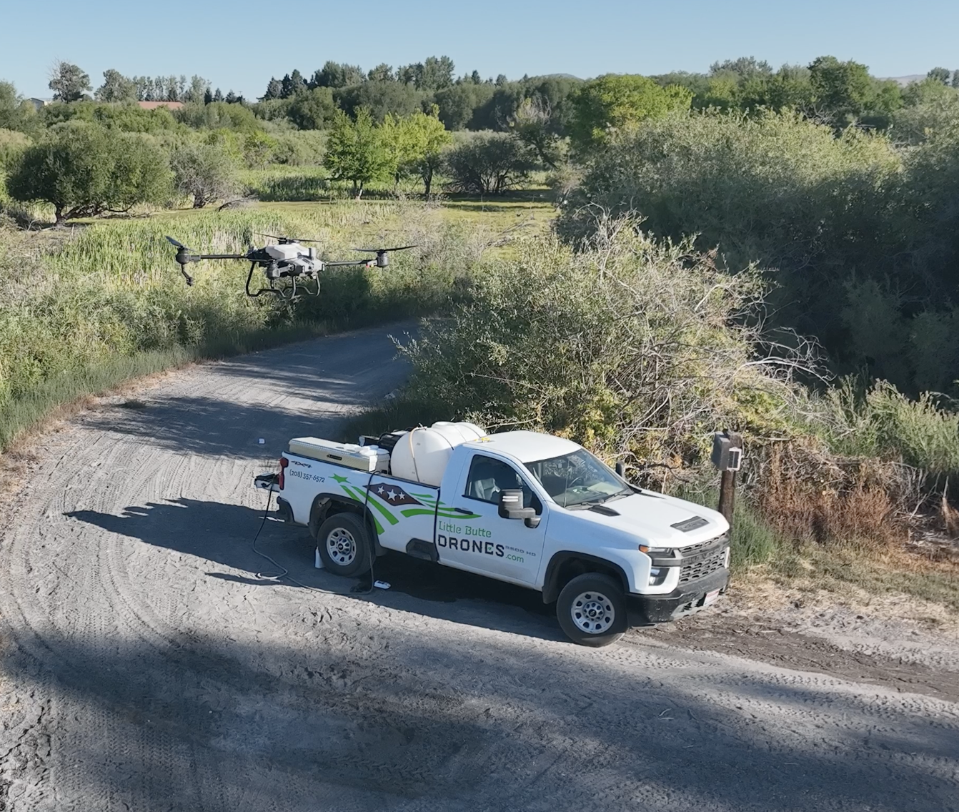 A Little Butte Drones support vehicle with the drone flying in marshlands nearby.