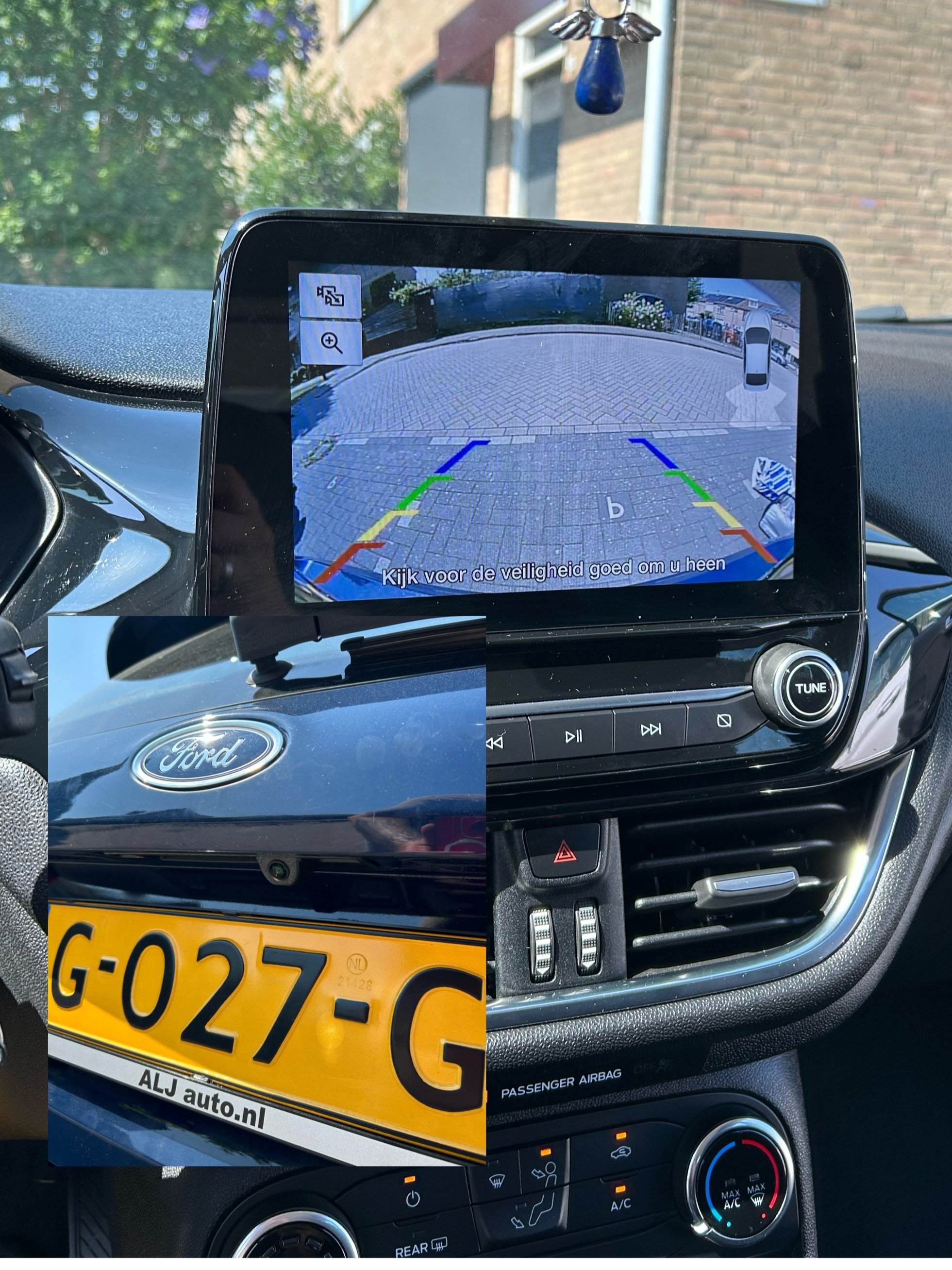 Binnenkant van een auto met achteruitkijkcamera op het scherm, een Ford-logo op de motorkap zichtbaar, een Nederlandse kentekenplaat, en het dashboard met klimaatregeling.