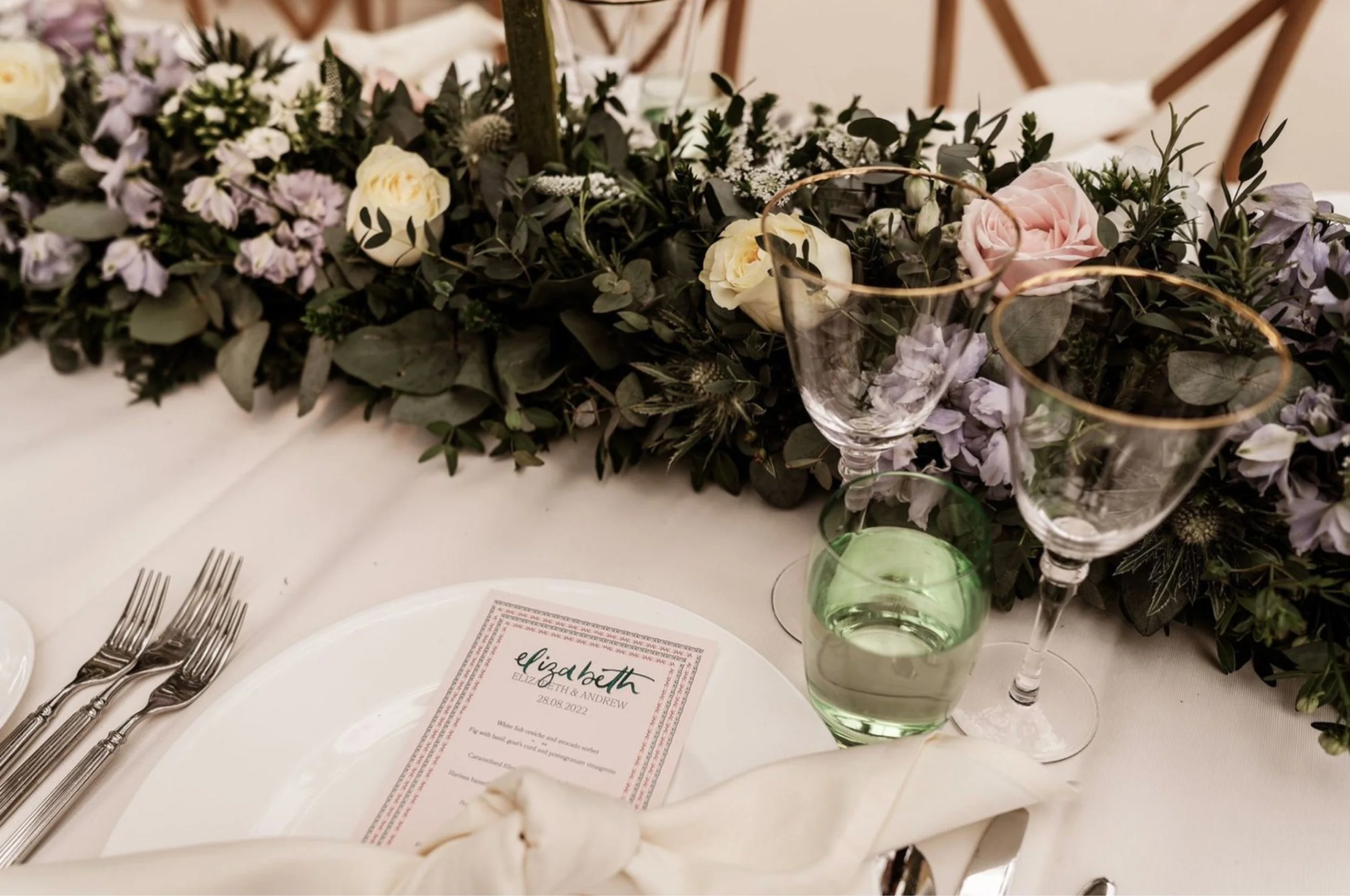 Elegant wedding table setting with custom menus, floral arrangements, and fine glassware in a sophisticated layout.