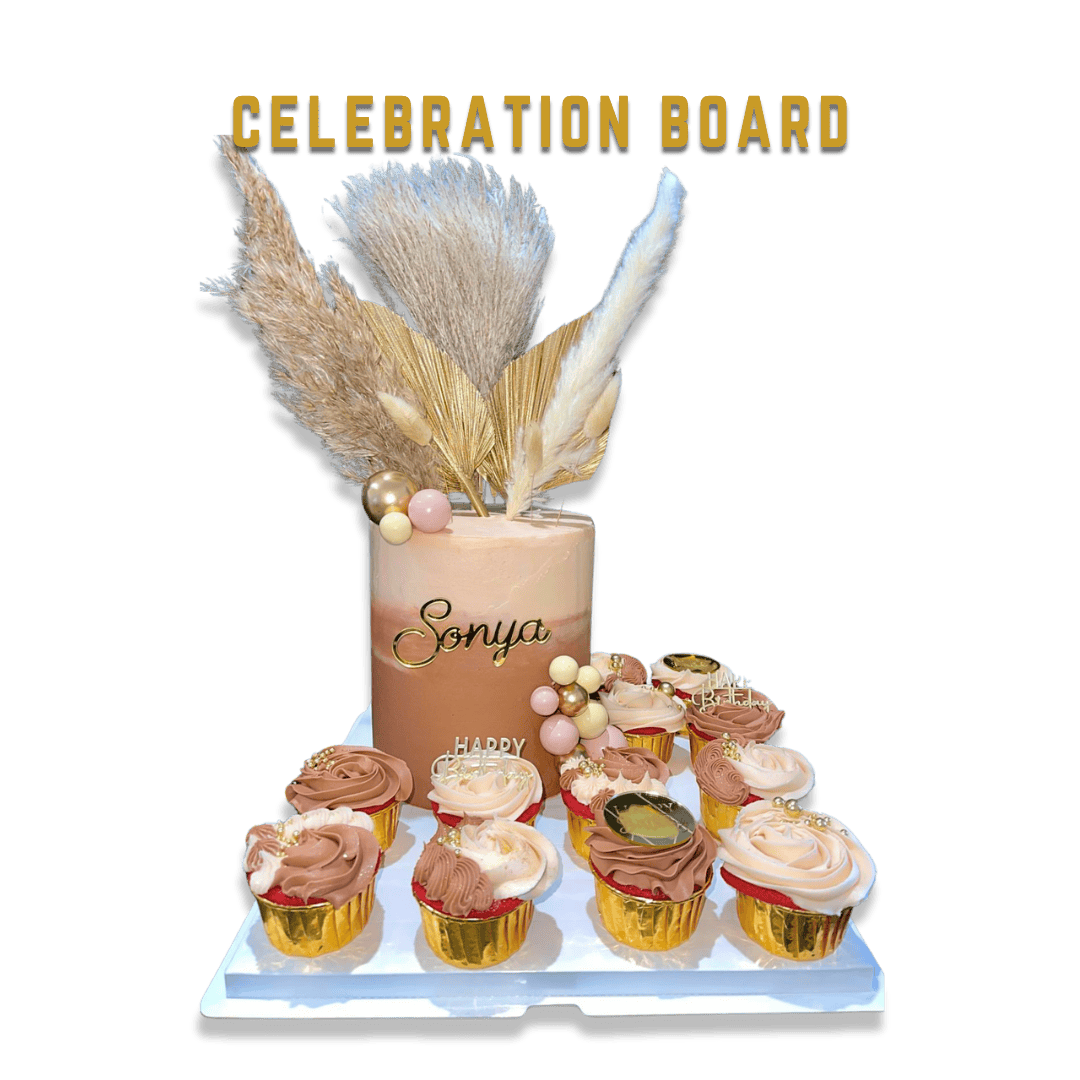 A celebration cake with the name 'Sonya' and an arrangement of cupcakes, decorated with pampas grass, gold and pink balls, and a 'Happy Birthday' topper, on a white tray against a black background.