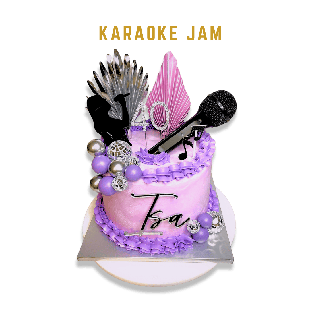 Karaoke Jam cake showcases a Double Barrel design with lilac buttercream covering the entire cake. A deeper purple buttercream lace decorates the top and bottom edges. The left side features an array of purple and silver embellished balls, some resem