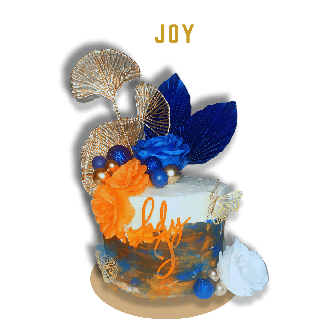 Joy Cake shows an elegant and artistic cake with a modern design. The cake is covered in a white base frosting with brushstrokes of blue, gold, and orange colors creating a textured, abstract look. The word "Joy" is displayed at the top of the image 