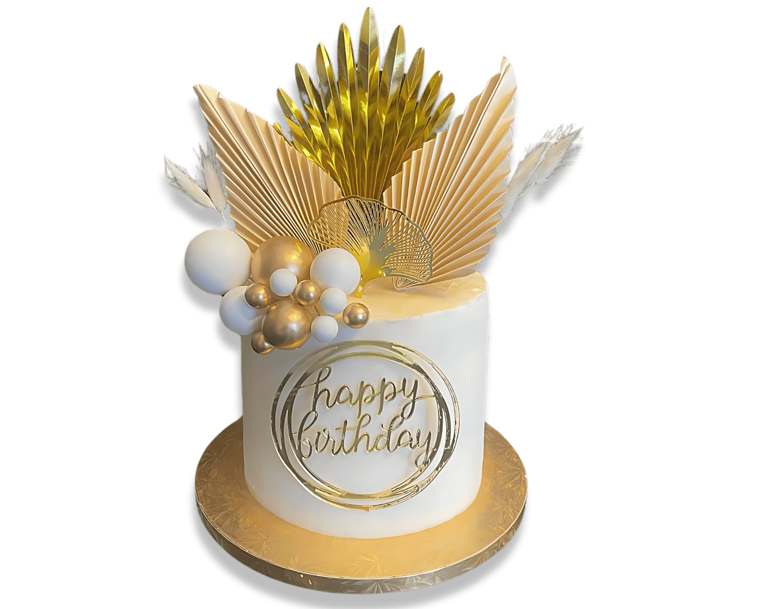 A white birthday cake decorated with gold and white ornaments, including spheres, feathers, and metallic leaves, with a gold 'happy birthday' inscription on the front, set on a gold base against a black background.