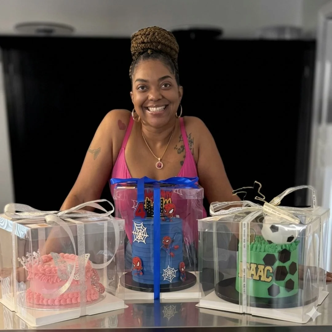 Woman smiling at a birthday celebration with three decorated cakes, each in clear gift boxes with ribbons, including a pink, blue, and green cake, with the middle cake featuring Spider-Man and web decorations.