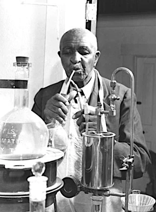 George Washington Carver working with laboratory glassware and scientific equipment in his laboratory.