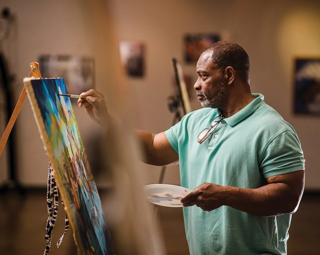 Image of artist Daryl Triplett painting at an easel in the Northeast Louisiana Delta African-American Heritage Museum.