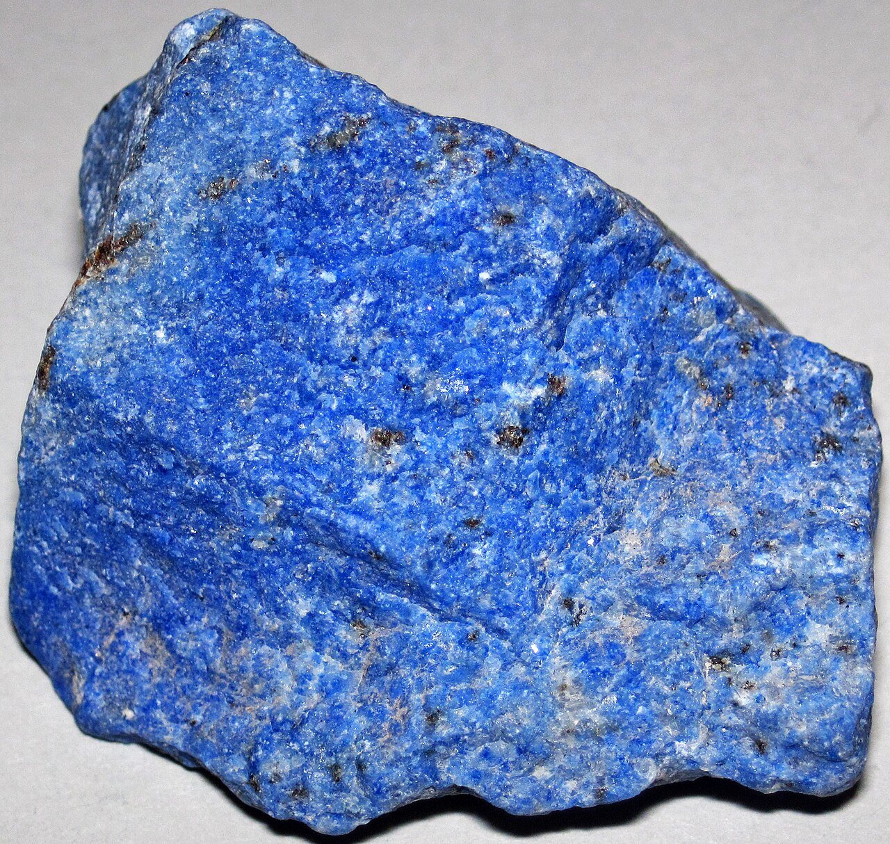 Blue lapis lazuli stone with white calcite and gold-colored pyrite inclusions.