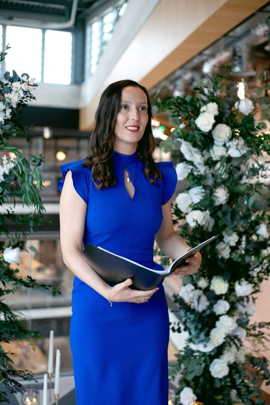 Fun and modern wedding celebrant holding folder during wedding ceremony