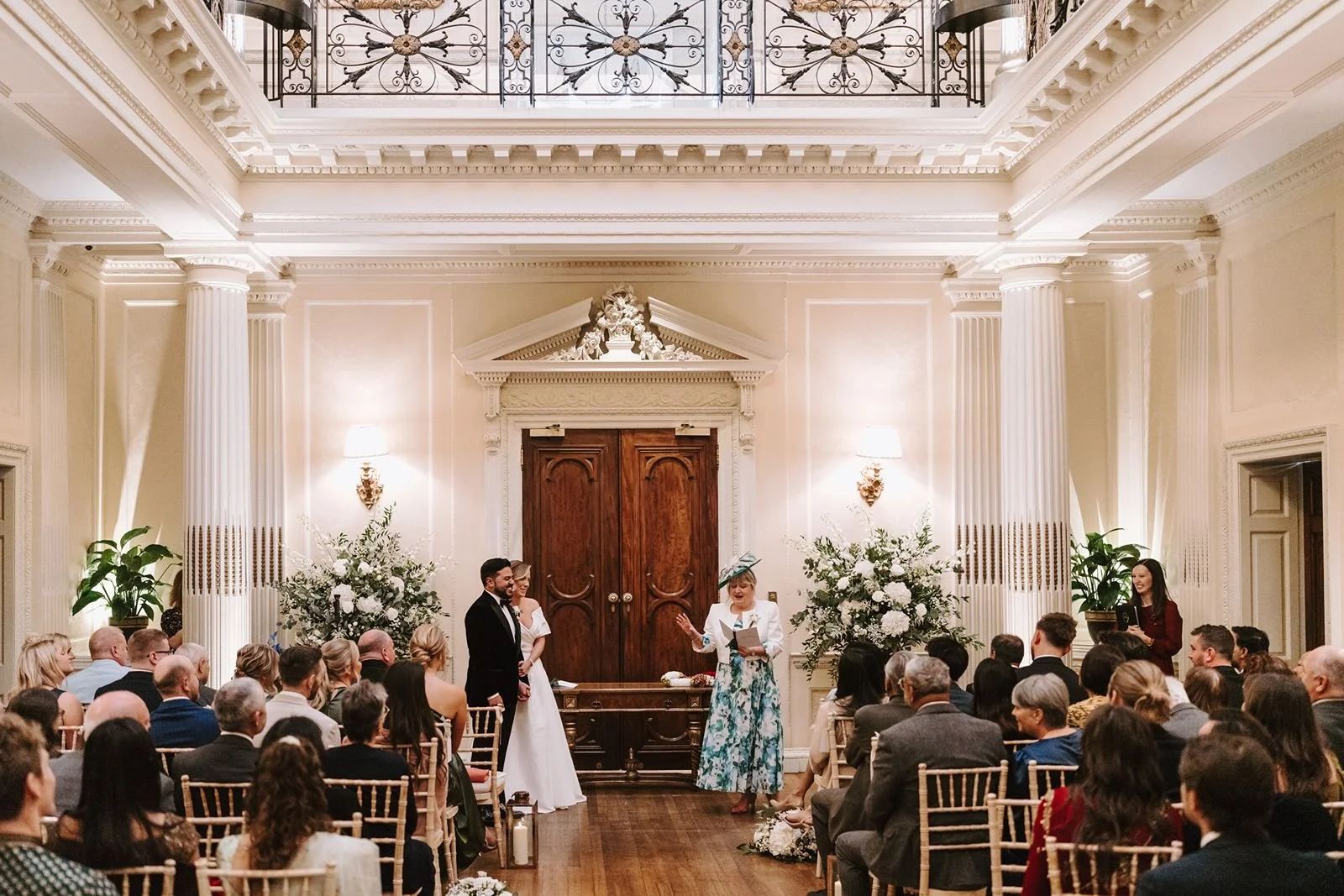 Bride and groom stnad in front of guests as Mum of Bride does a reading