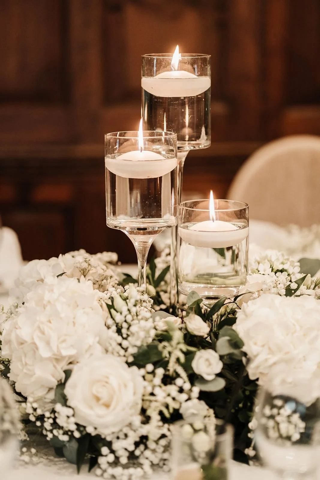 3 clear glass candlestick with water and flower surround table centre