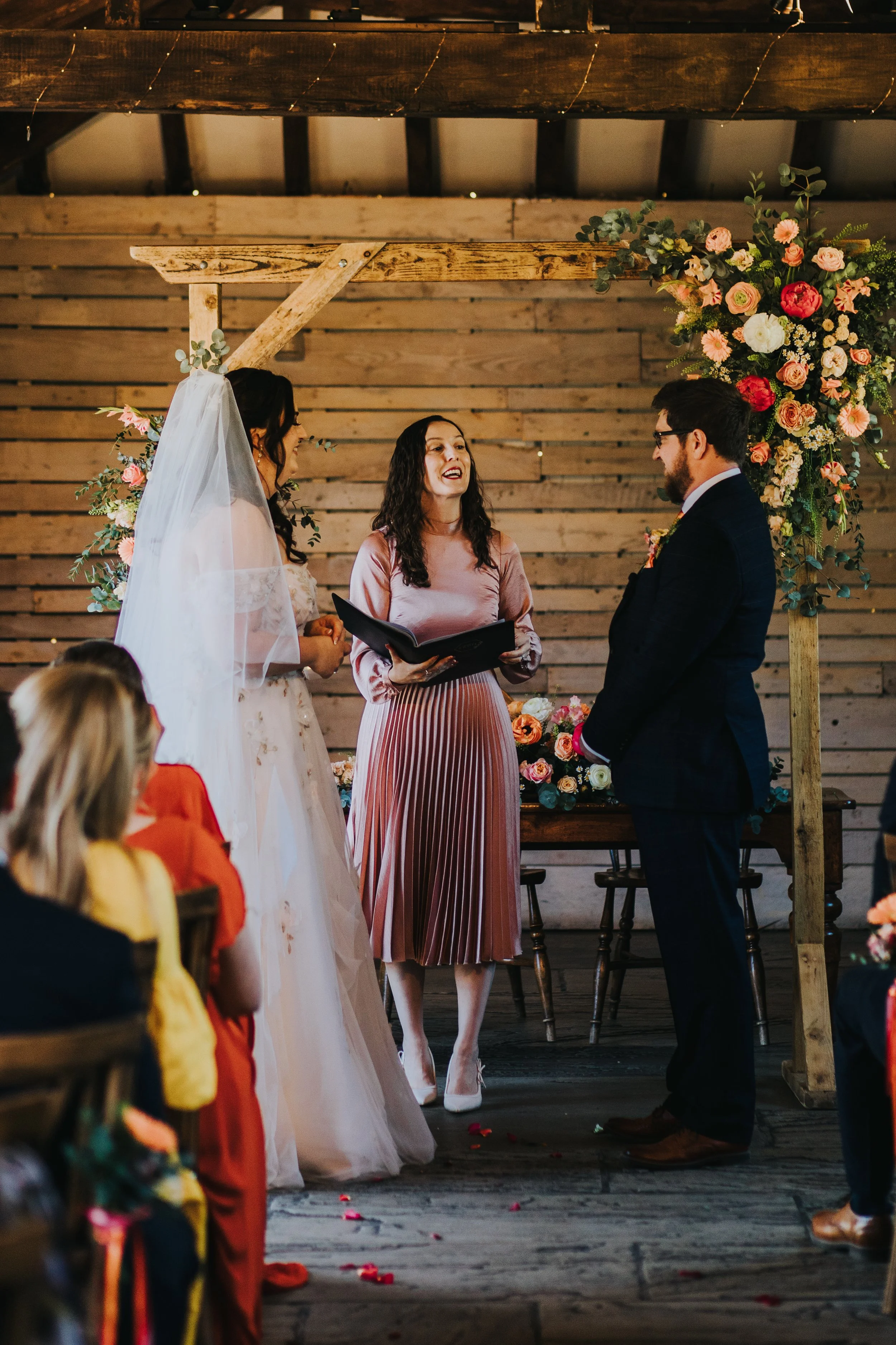 Celebrant reading to smiling couple during wedding ceremony.JPG