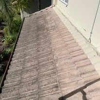 A view of a sloped rooftop covered with weathered clay tiles.