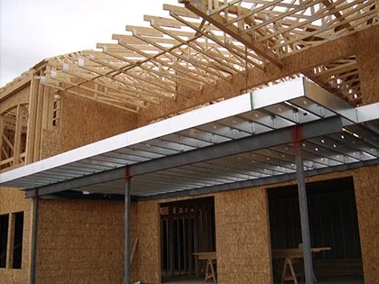 View looking up at a house being built with a steel framed elevated deck