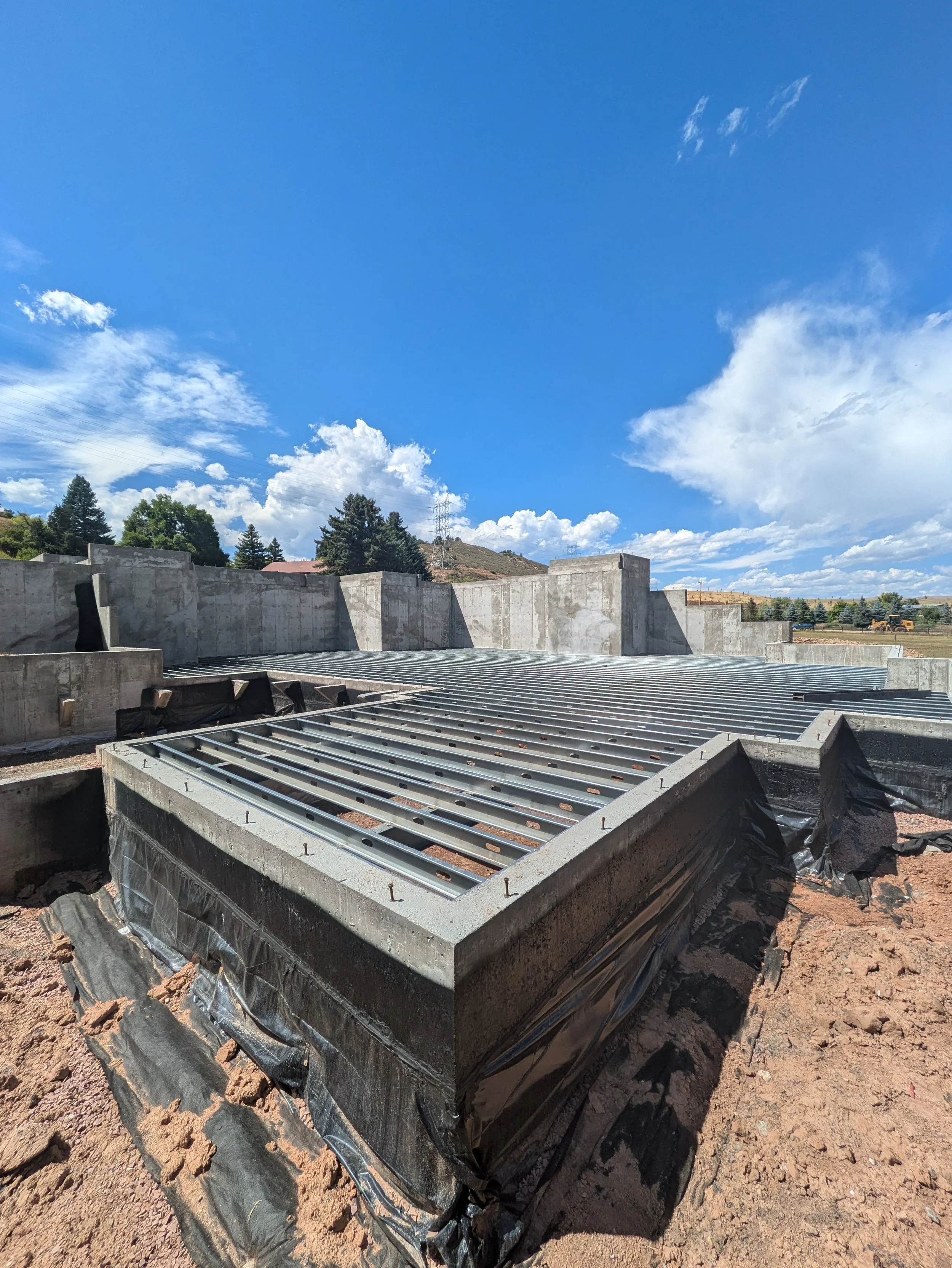 Steel joists being installed for a structural floor in Colorado with a blue sky in the background