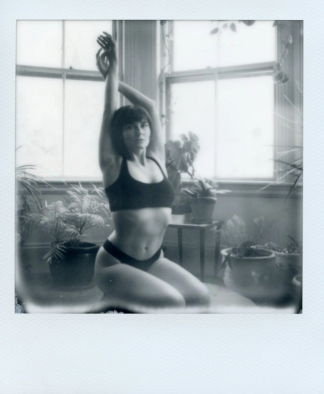 Woman with her arms up in bed by the windows