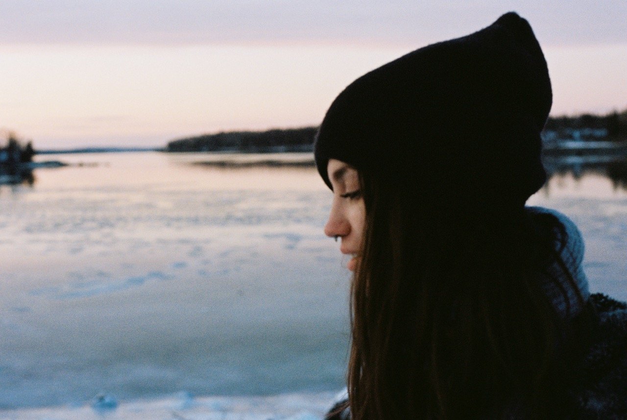 Peaceful looking woman by the ocean wearing a beanie