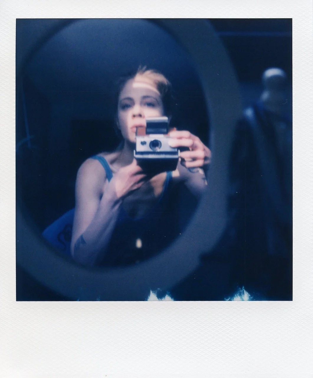 Kate taking a self portrait with her polaroid camera in the mirror