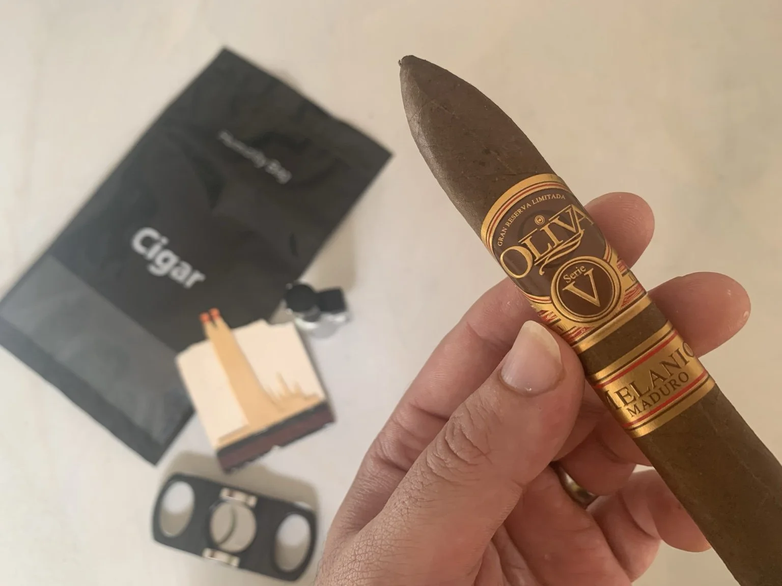 Oliva Serie V Melanio Maduro cigar close-up with cutter and lighter on table