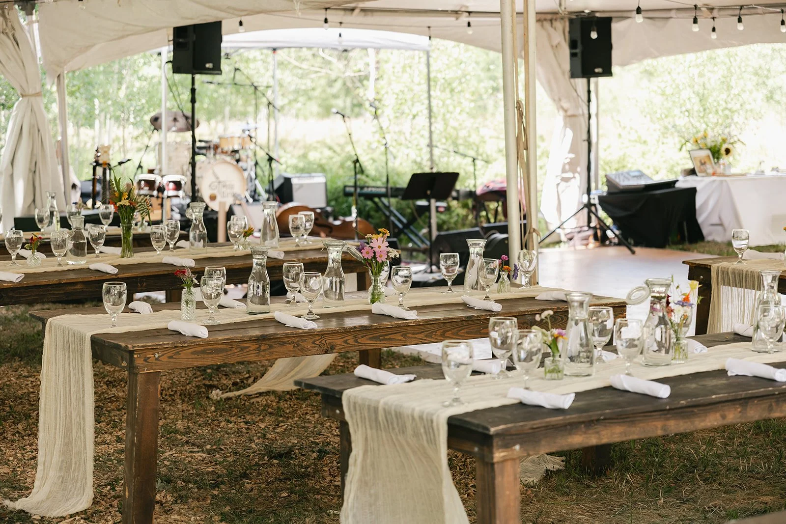 Farm tables, bistro lights, and dance floor in a tent for wedding 