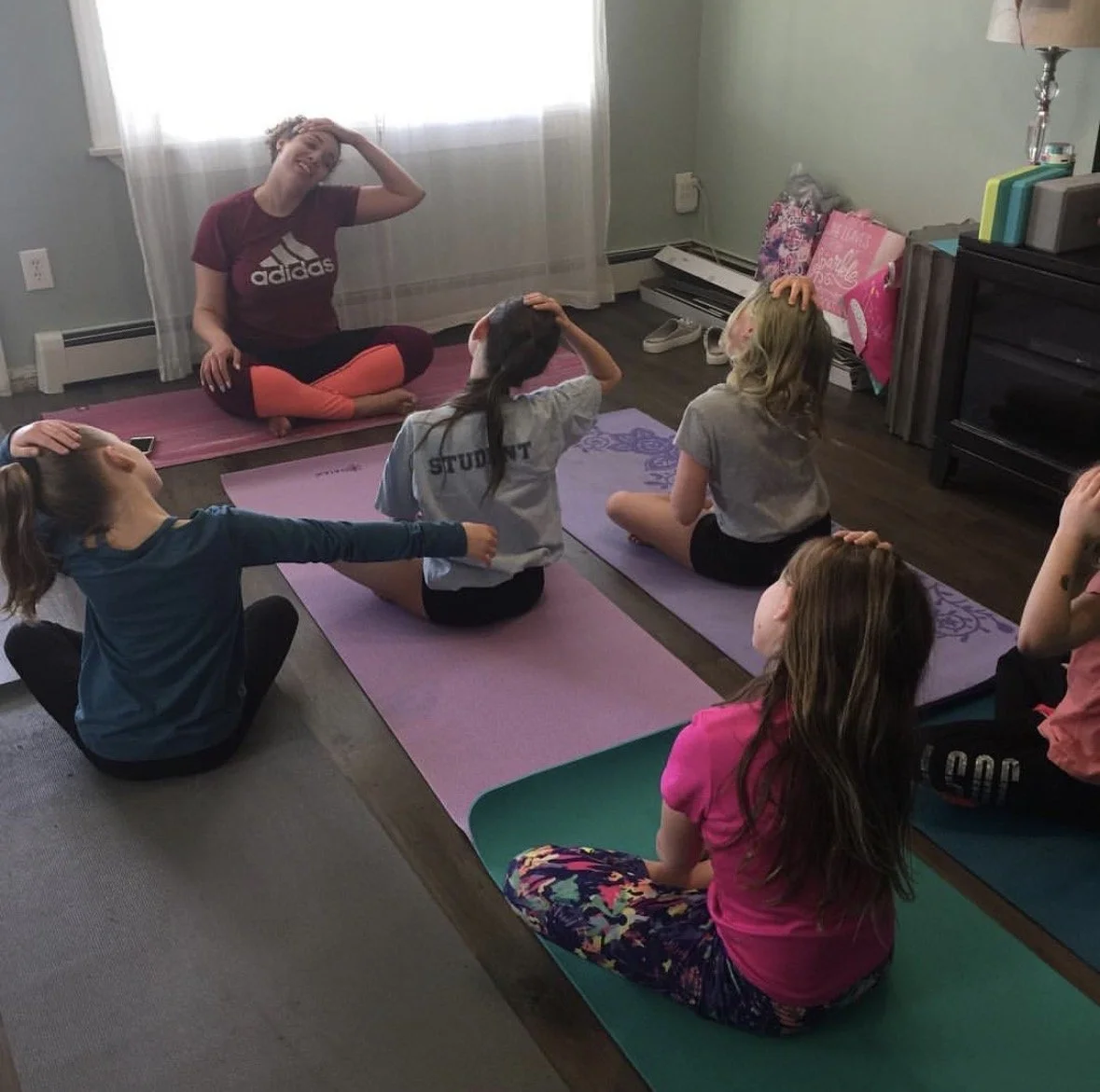 Children participating in a yoga class with an instructor in a living room.