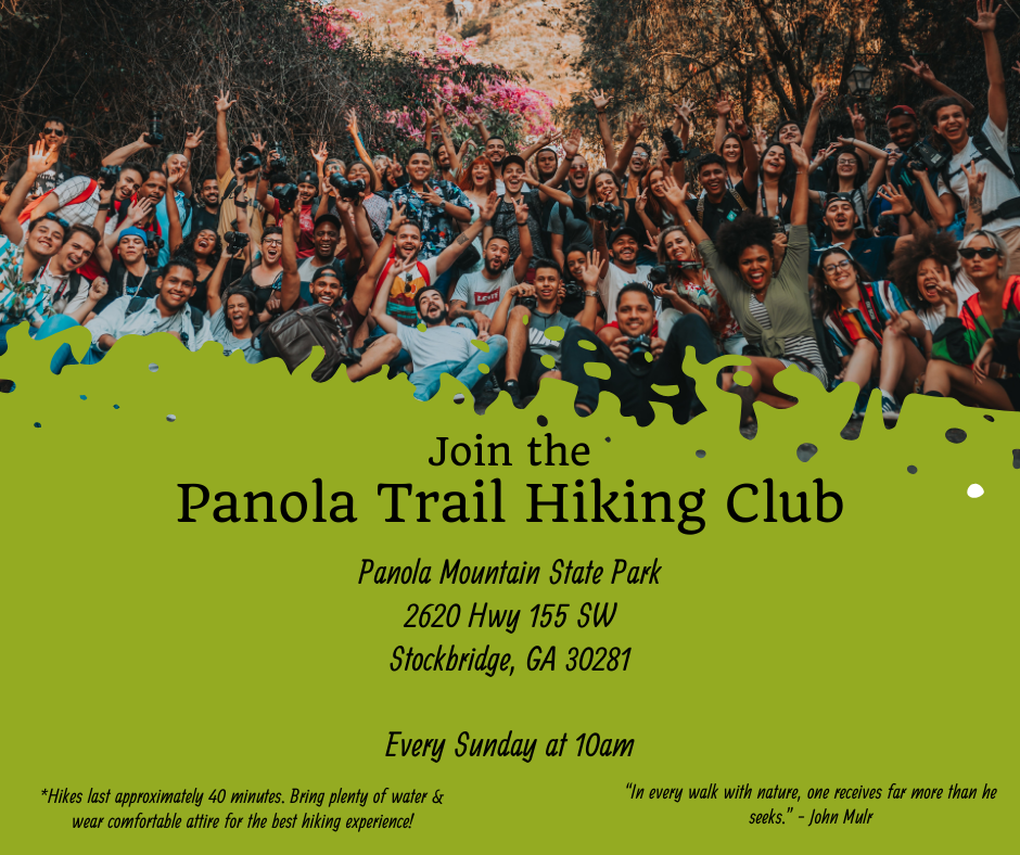 A large group of diverse people outdoors, smiling and raising their hands in celebration, with trees and flowers in the background.