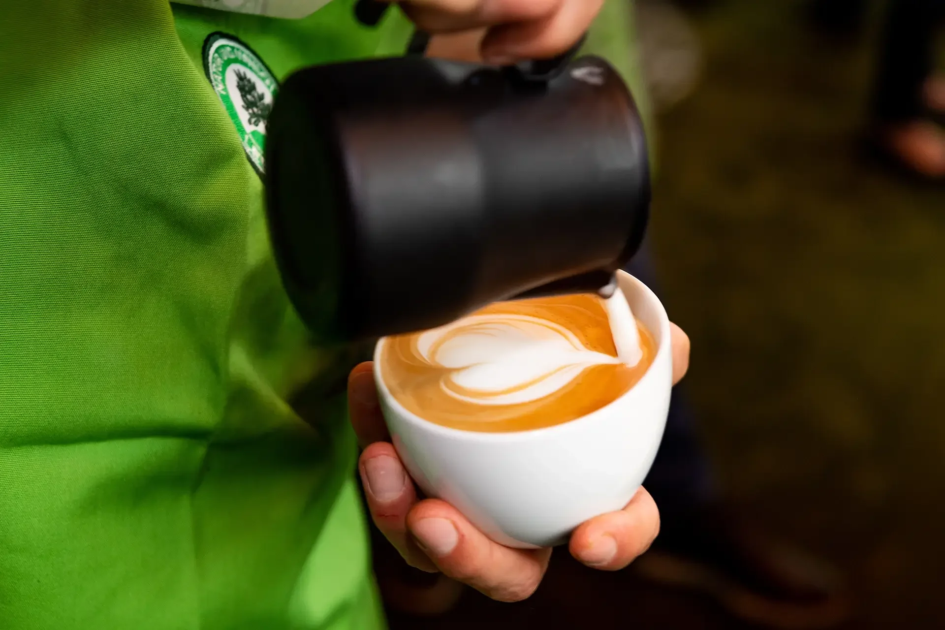 Ein Barista gießt Late Art in Herzform