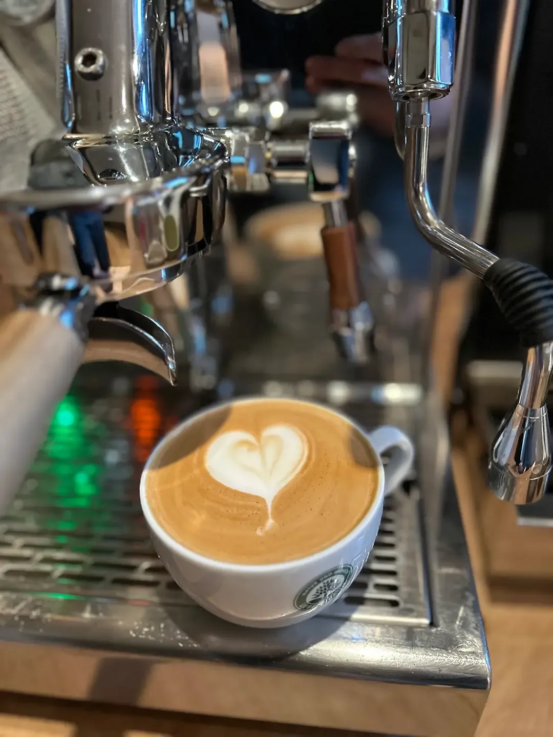 Ein Cappuccino mit Latte Art steht auf der Abtropfschale einer Siebträgermaschine