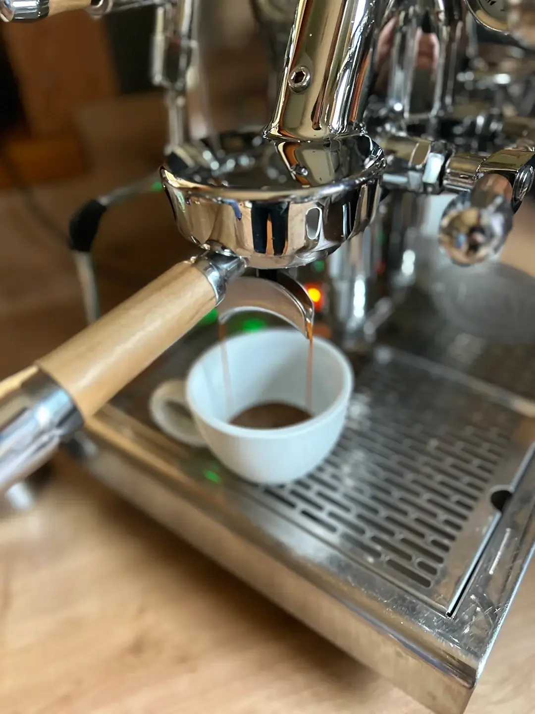 Ein Espresso läuft aus einer Siebträgermaschine in eine Cappuccinotasse