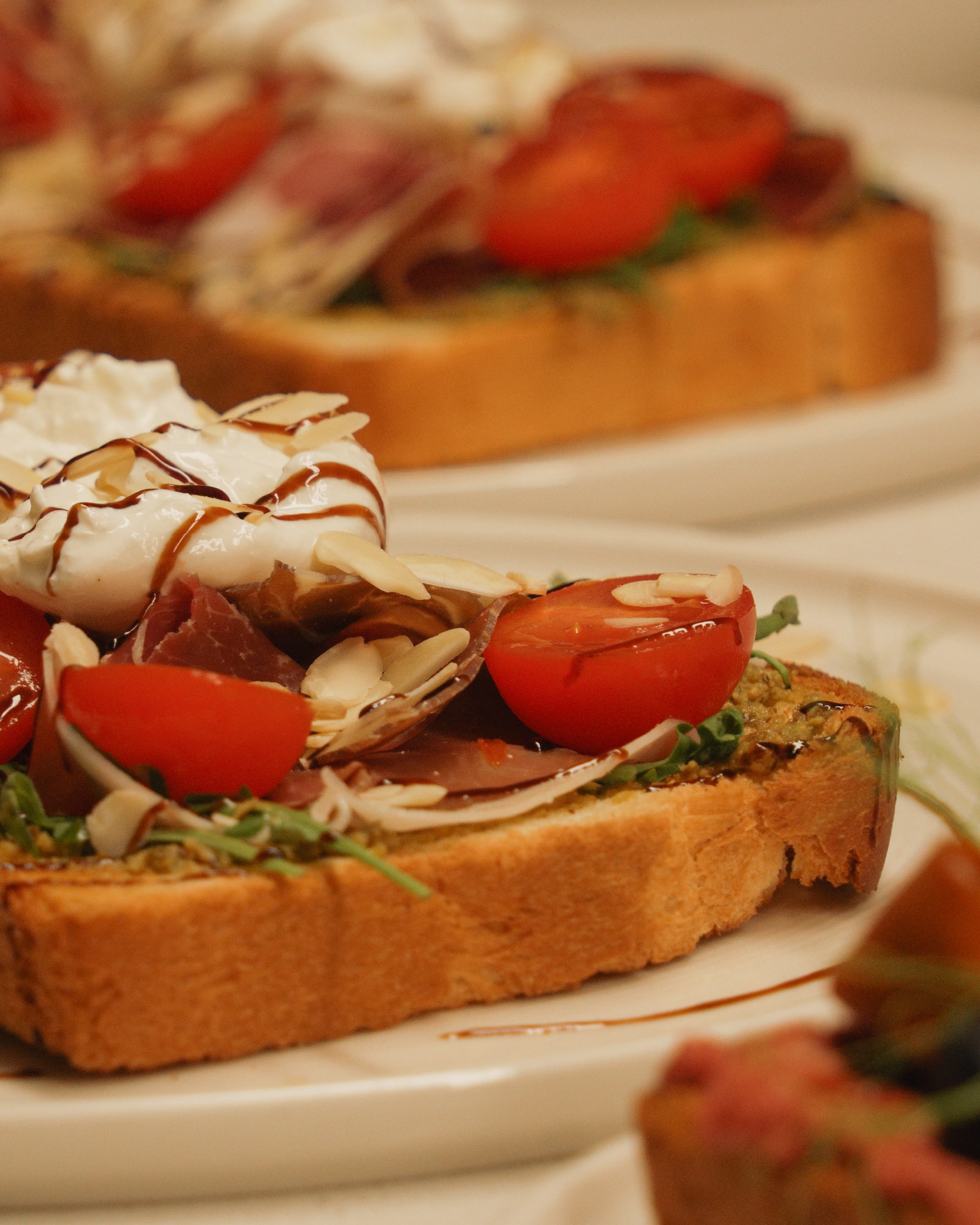 Close-up of an open-faced toast with sliced tomatoes, herbs, and cheese on toasted bread, named The Italian Toast.