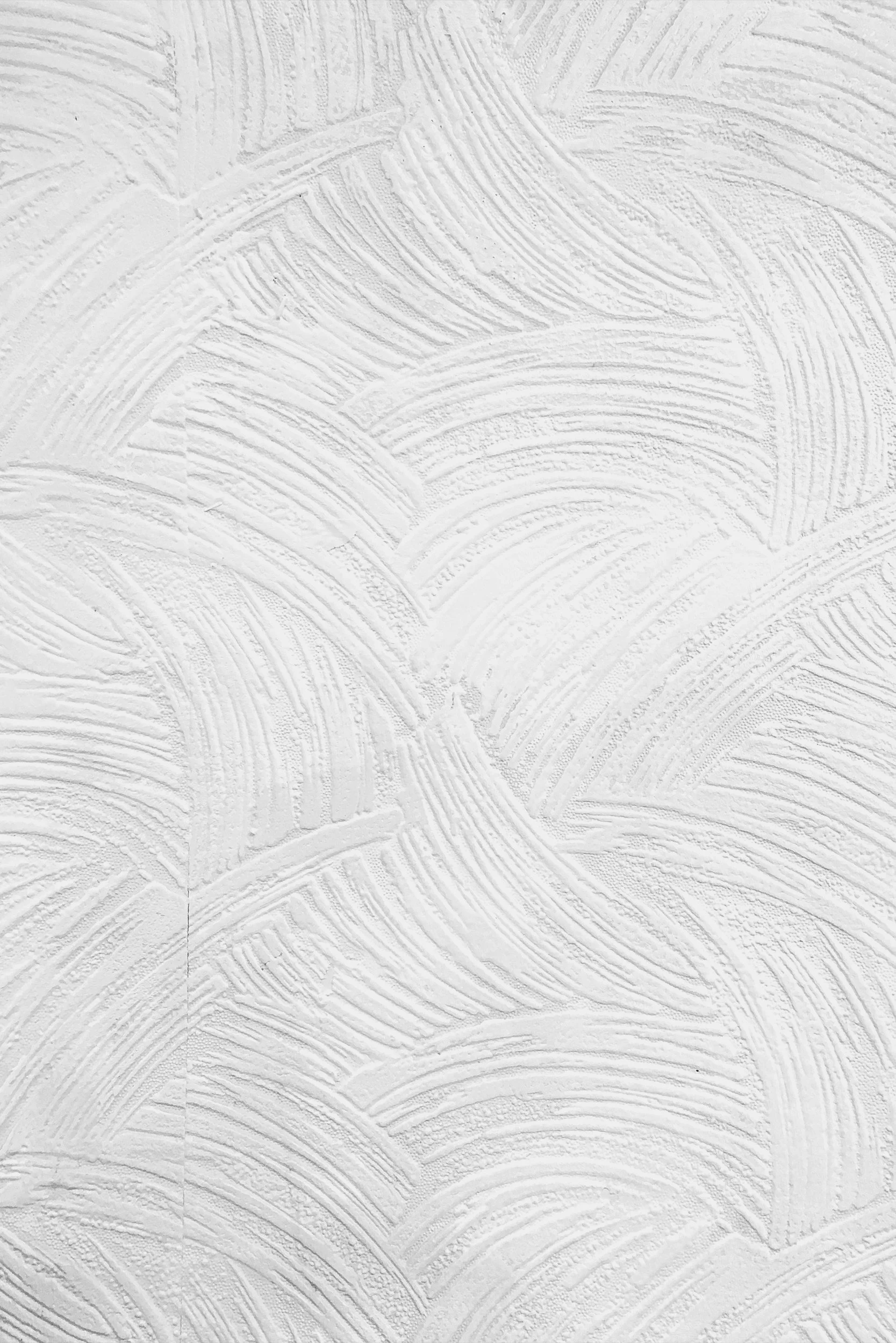 Close-up of a white textured wall with a swirling pattern and brushstroke-like designs.