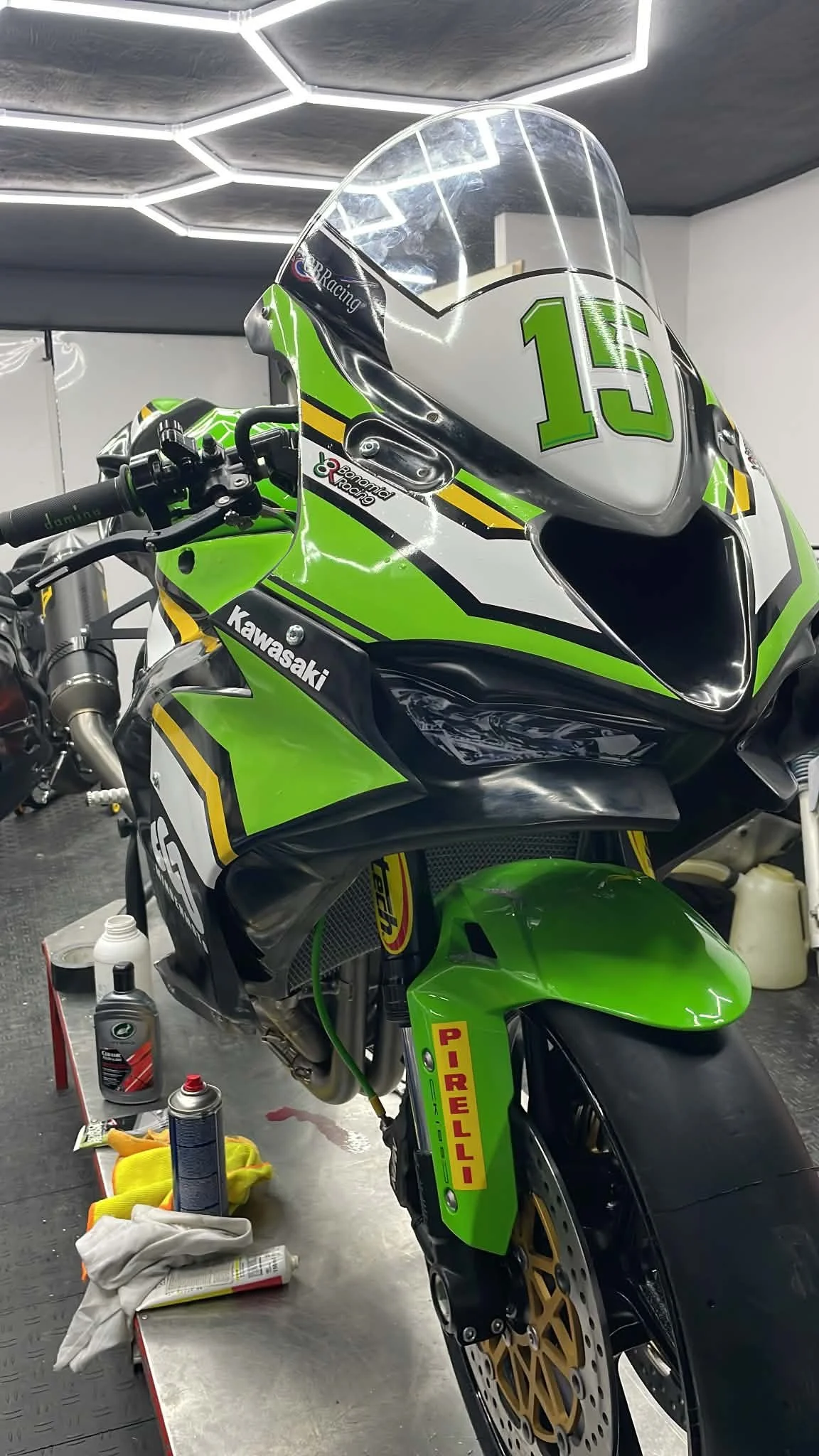 Front view of the number 15 Kawasaki race bike in the Minden Moto workshop