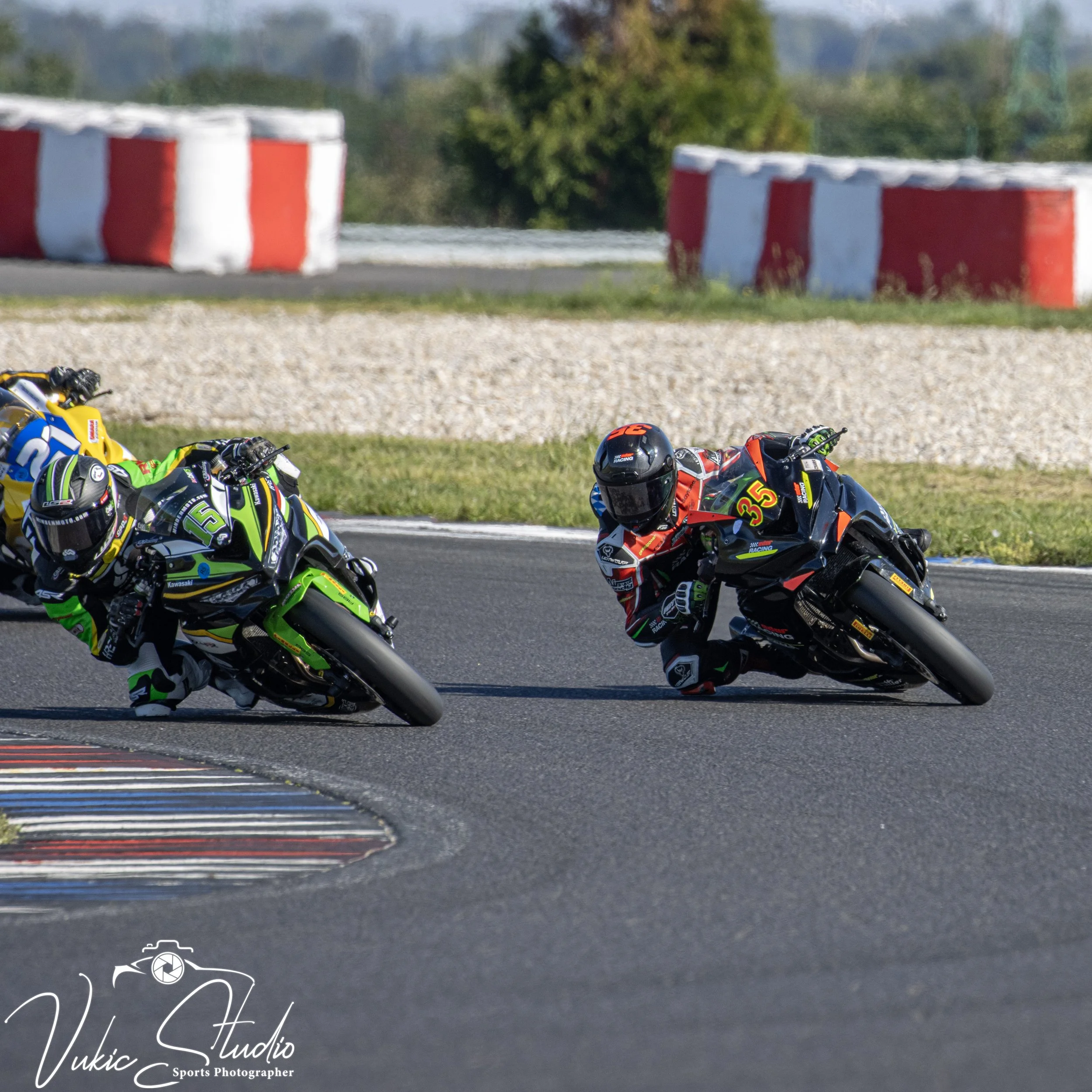 Motorcycle racers leaning into a turn on a race track, wearing colorful racing suits and helmets.