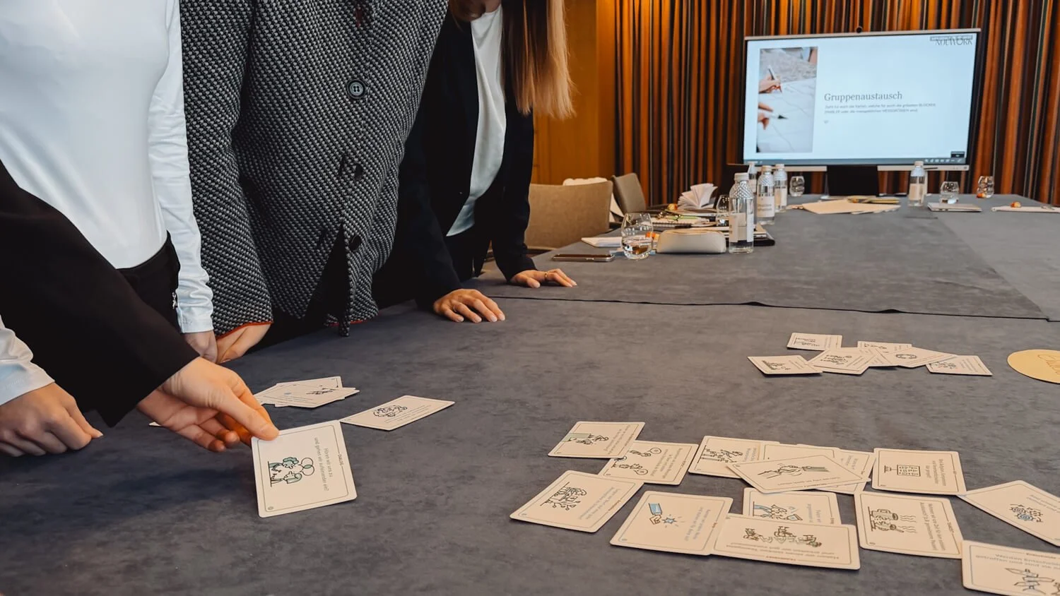 Business workshop participants discussing strategy cards around a conference table during corporate training session.