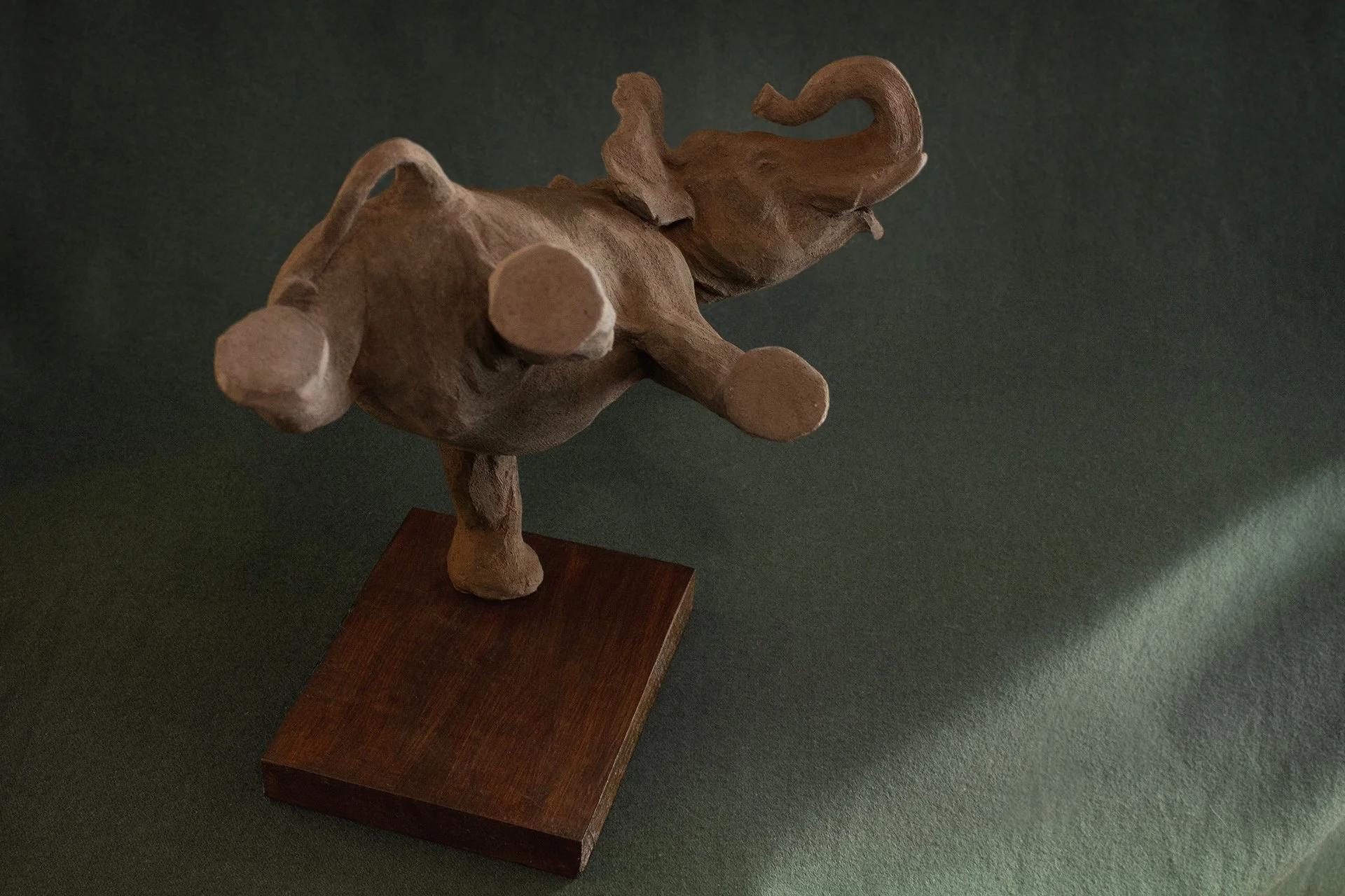 Sculpture en terre. Un éléphant en apesanteur nage sous l’eau et touche le fond de la patte. Clay sculpture. A weightless elephant swims underwater, touching the bottom with its foot.