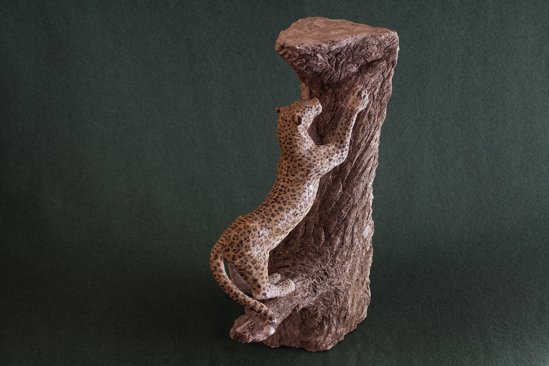 Sculpture terre. Une panthère fait ses griffes sur un vieux tronc. Clay sculpture. A panther is sharpening its claws on an old tree trunk.