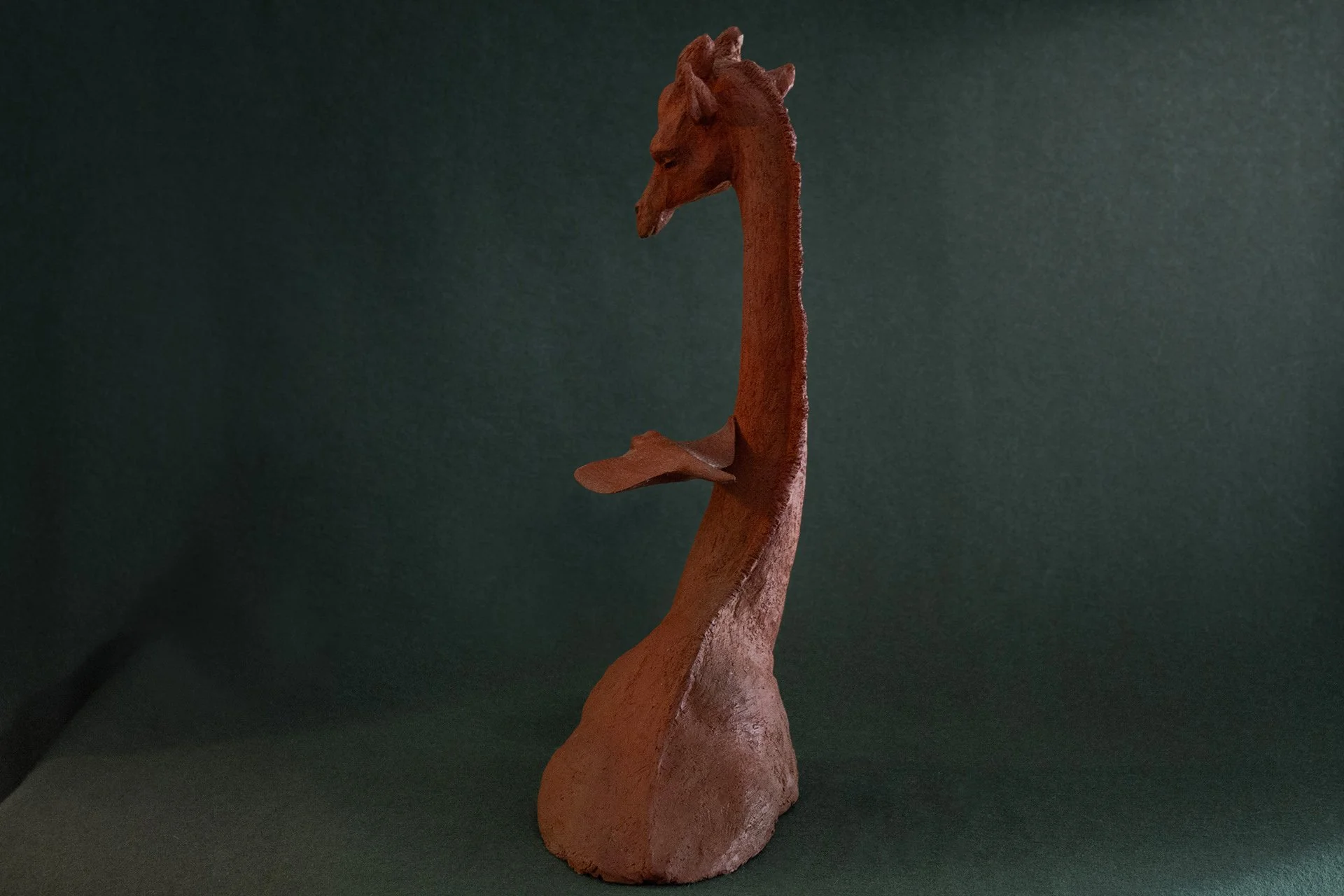 Sculpture en terre. Une girafe aquatique est émue par une raie qui lui frôle le cou. Clay sculpture. An aquatic giraffe is moved by a ray that brushes against its neck.