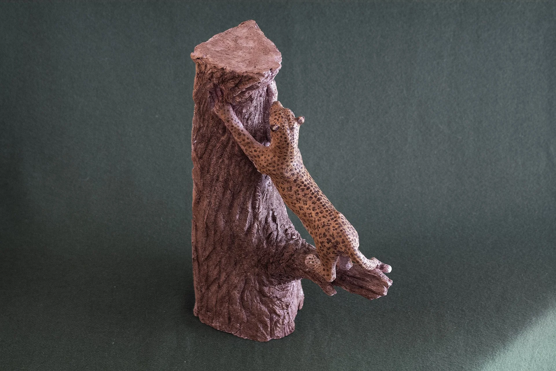 Sculpture terre. Une panthère fait ses griffes sur un vieux tronc. Clay sculpture. A panther is sharpening its claws on an old tree trunk.