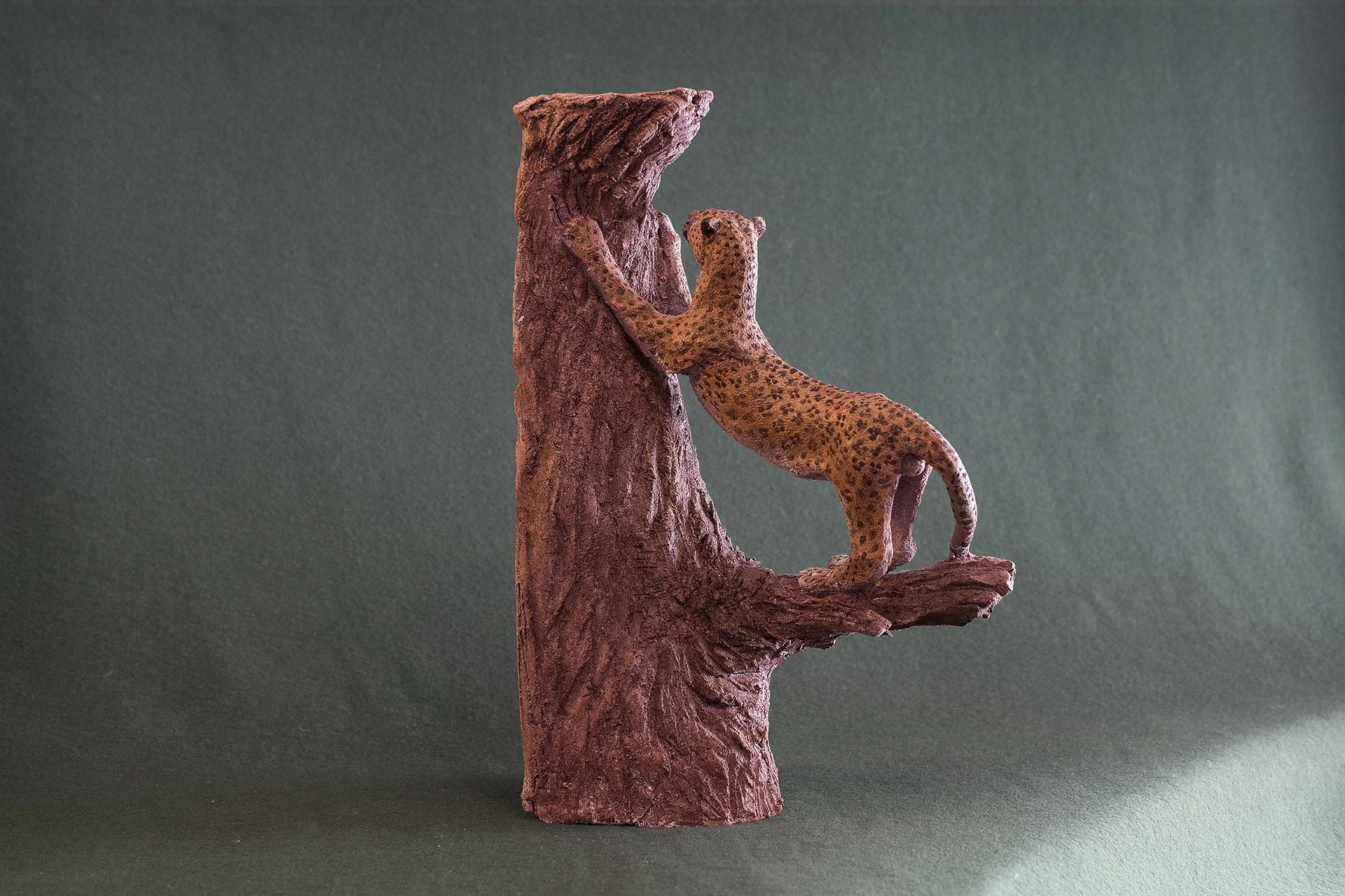 Sculpture terre. Une panthère fait ses griffes sur un vieux tronc. Clay sculpture. A panther is sharpening its claws on an old tree trunk.