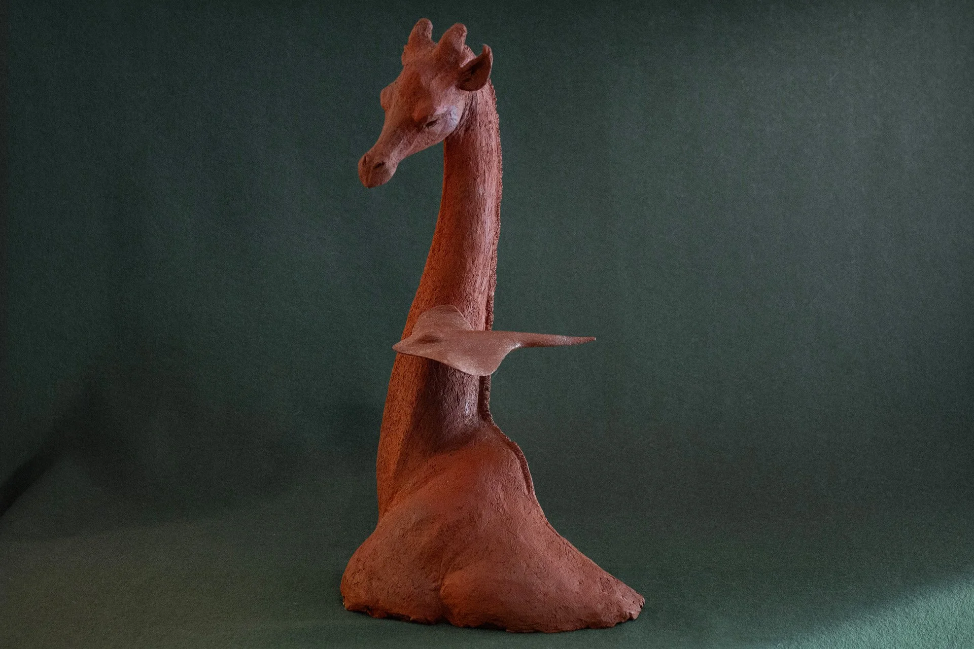 Sculpture en terre. Une girafe aquatique est émue par une raie qui lui frôle le cou. Clay sculpture. An aquatic giraffe is moved by a ray that brushes against its neck.