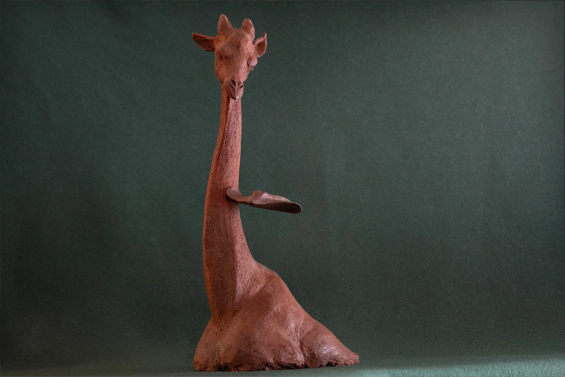 Sculpture en terre. Une girafe aquatique est émue par une raie qui lui frôle le cou. Clay sculpture. An aquatic giraffe is moved by a ray that brushes against its neck.