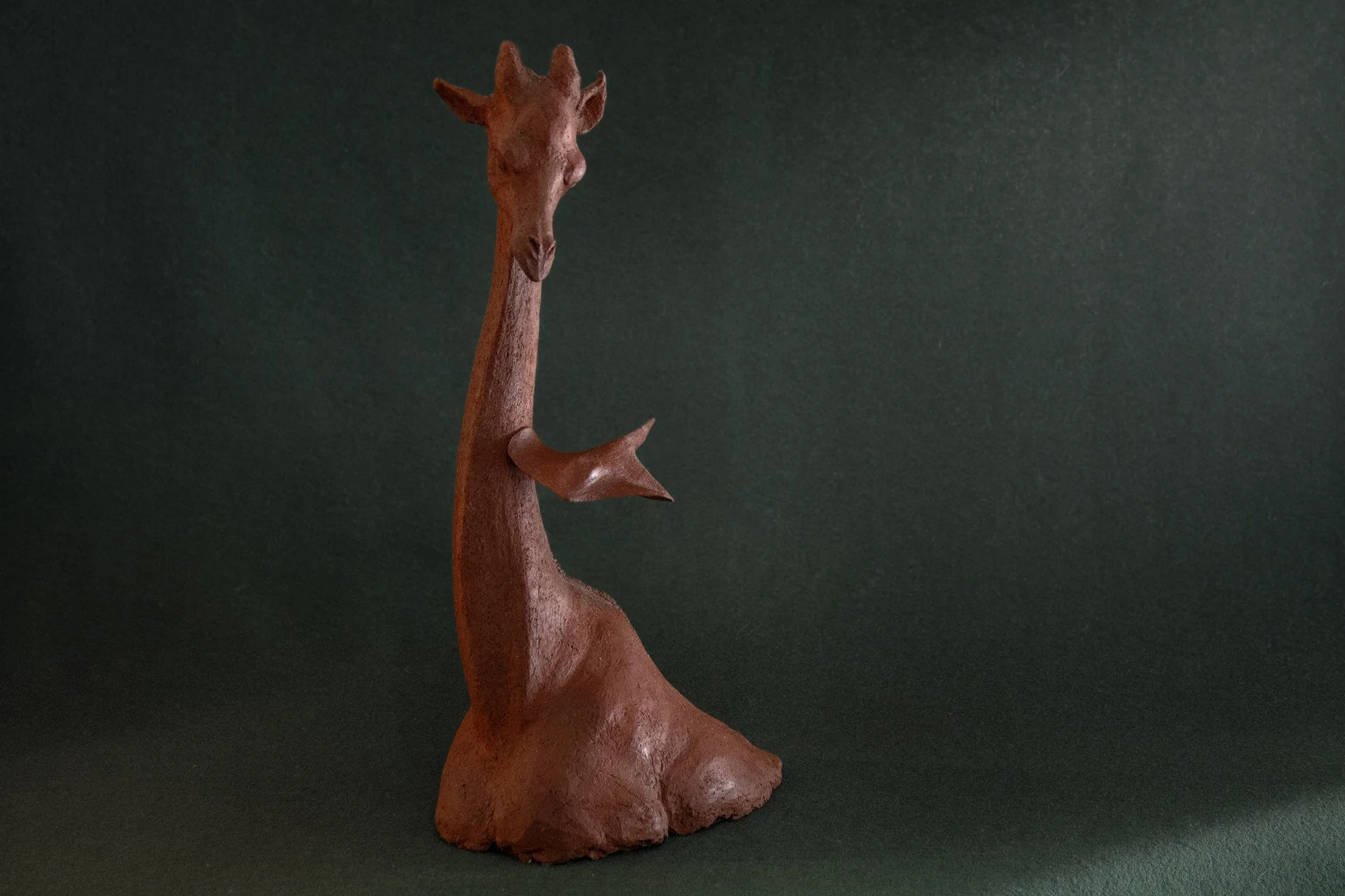 Sculpture en terre. Une girafe aquatique est émue par une raie qui lui frôle le cou. Clay sculpture. An aquatic giraffe is moved by a ray that brushes against its neck.