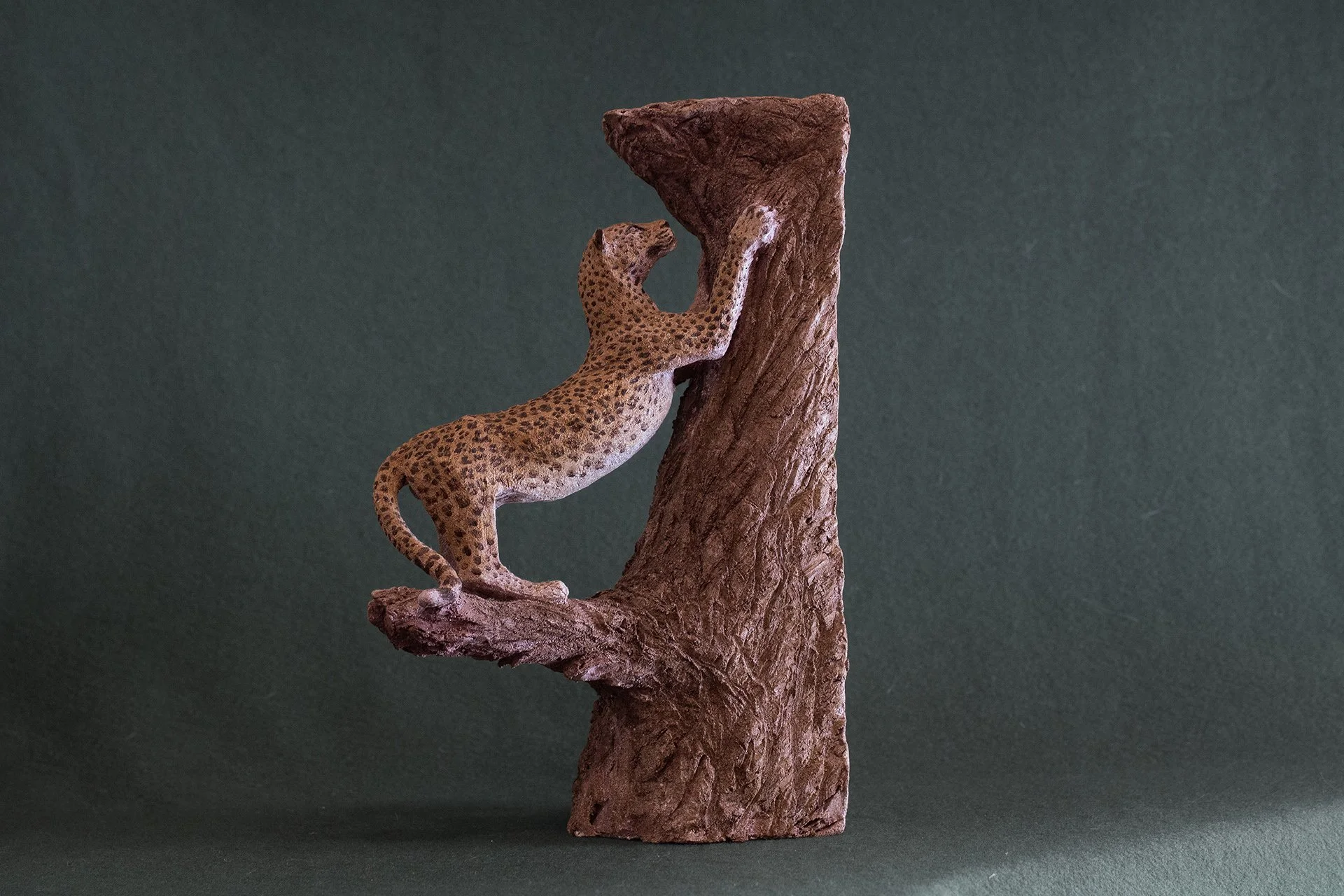 Sculpture terre. Une panthère fait ses griffes sur un vieux tronc. Clay sculpture. A panther is sharpening its claws on an old tree trunk.