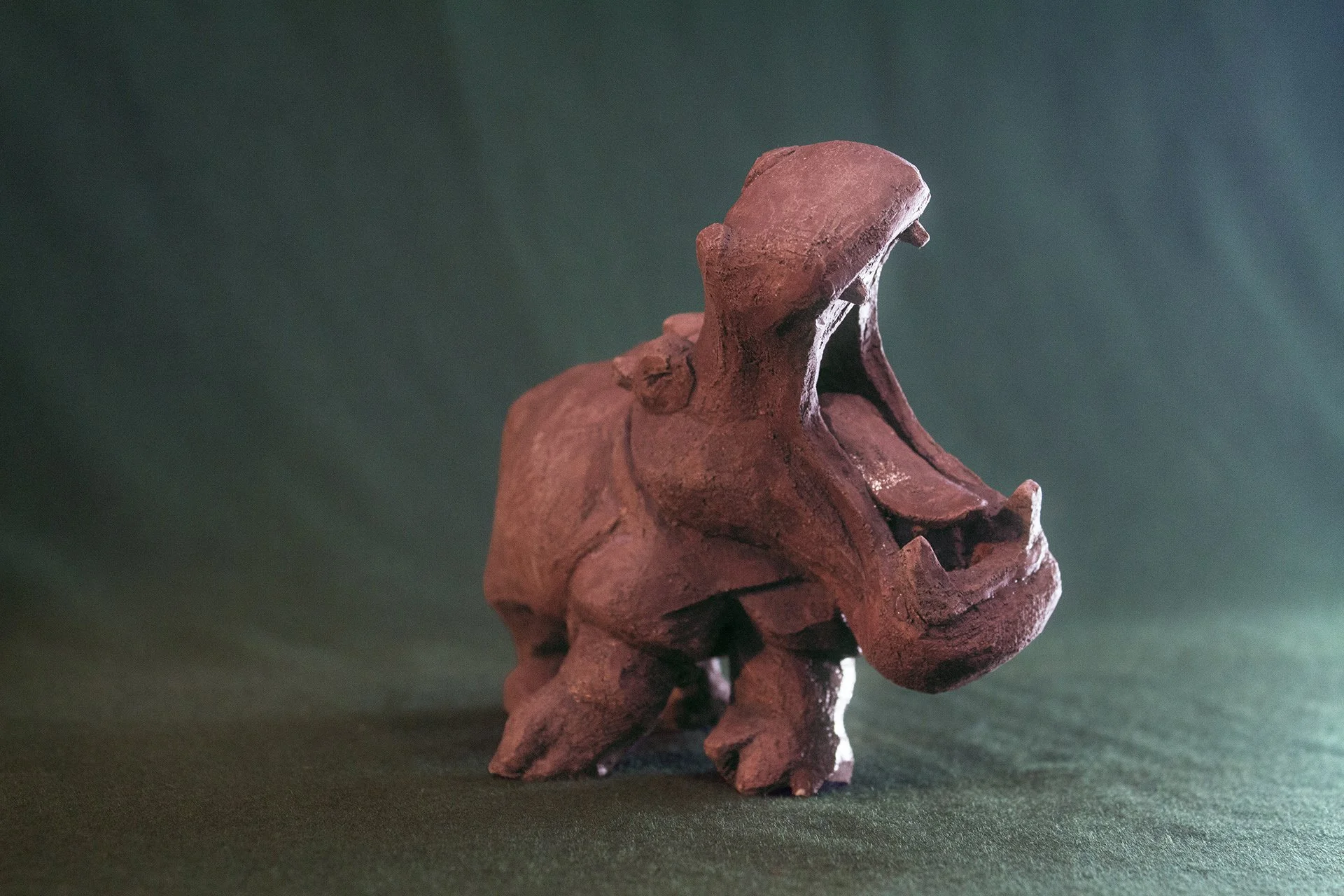 Sculpture terre. Un hippopotame chante la gueule grande ouverte. Clay sculpture. A hippopotamus sings with its mouth wide open.