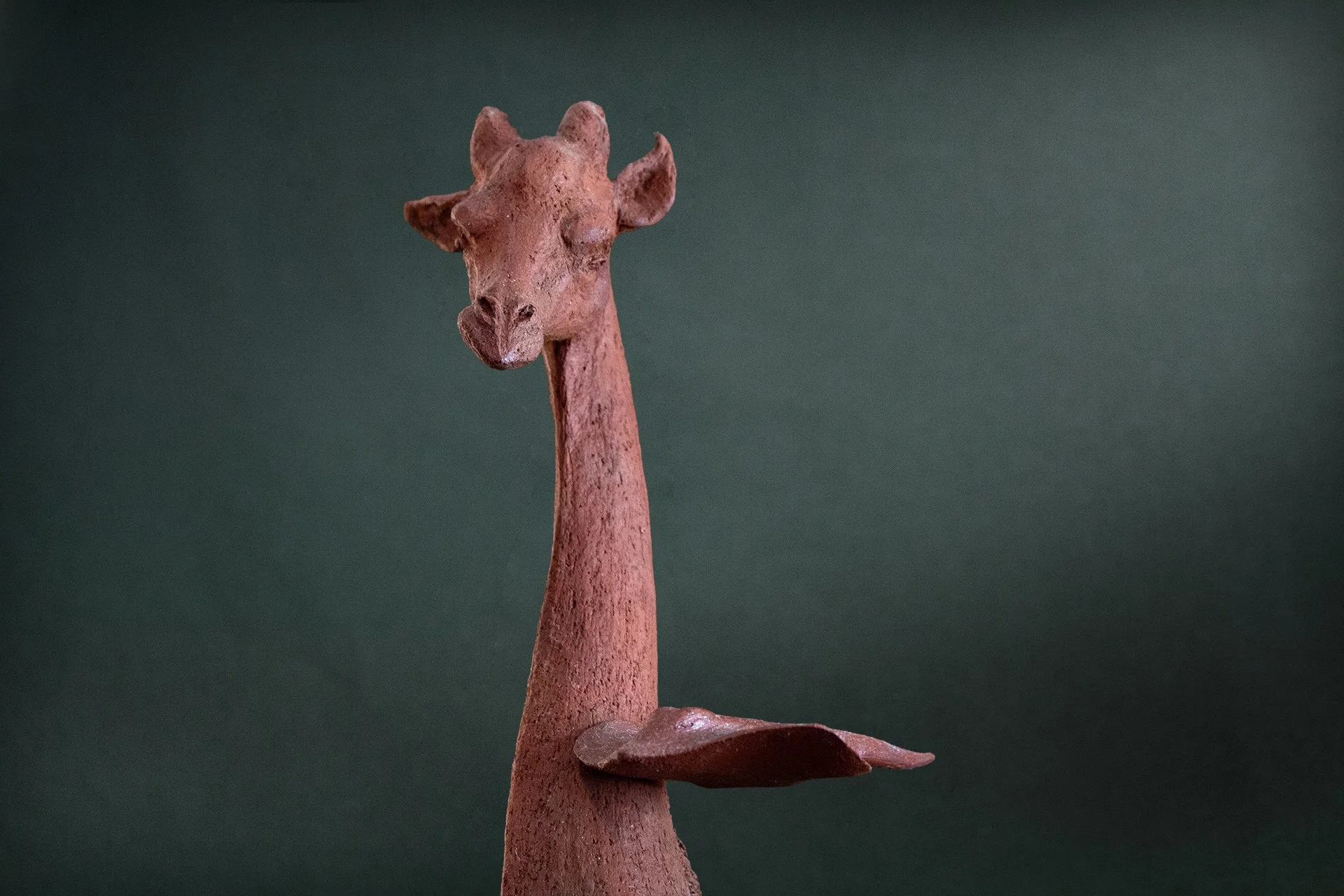 Sculpture en terre. Une girafe aquatique est émue par une raie qui lui frôle le cou. Clay sculpture. An aquatic giraffe is moved by a ray that brushes against its neck.