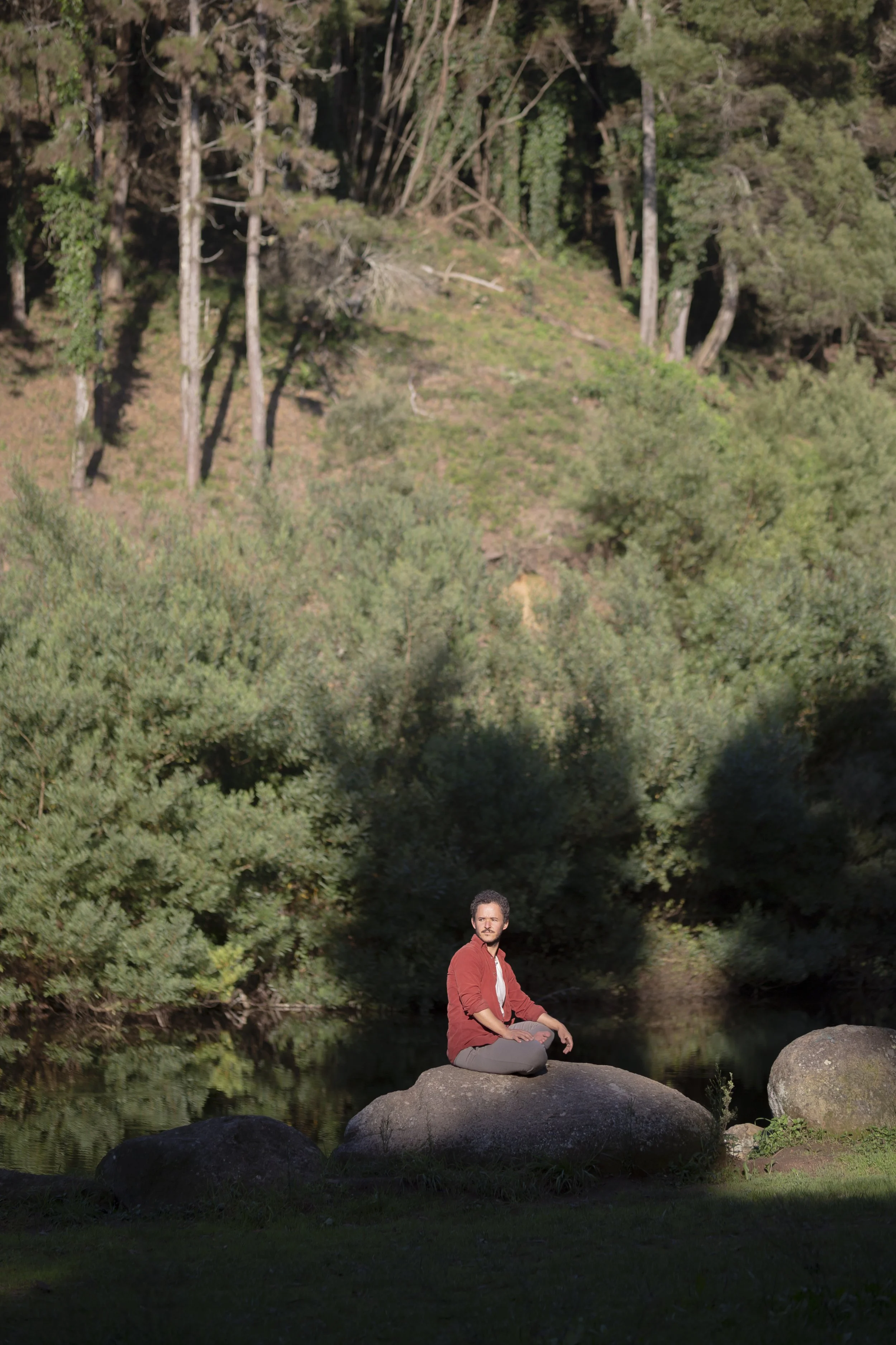 Pedro sitting on stone by mountain lake in Portugal after somatic breakthrough and trauma healing