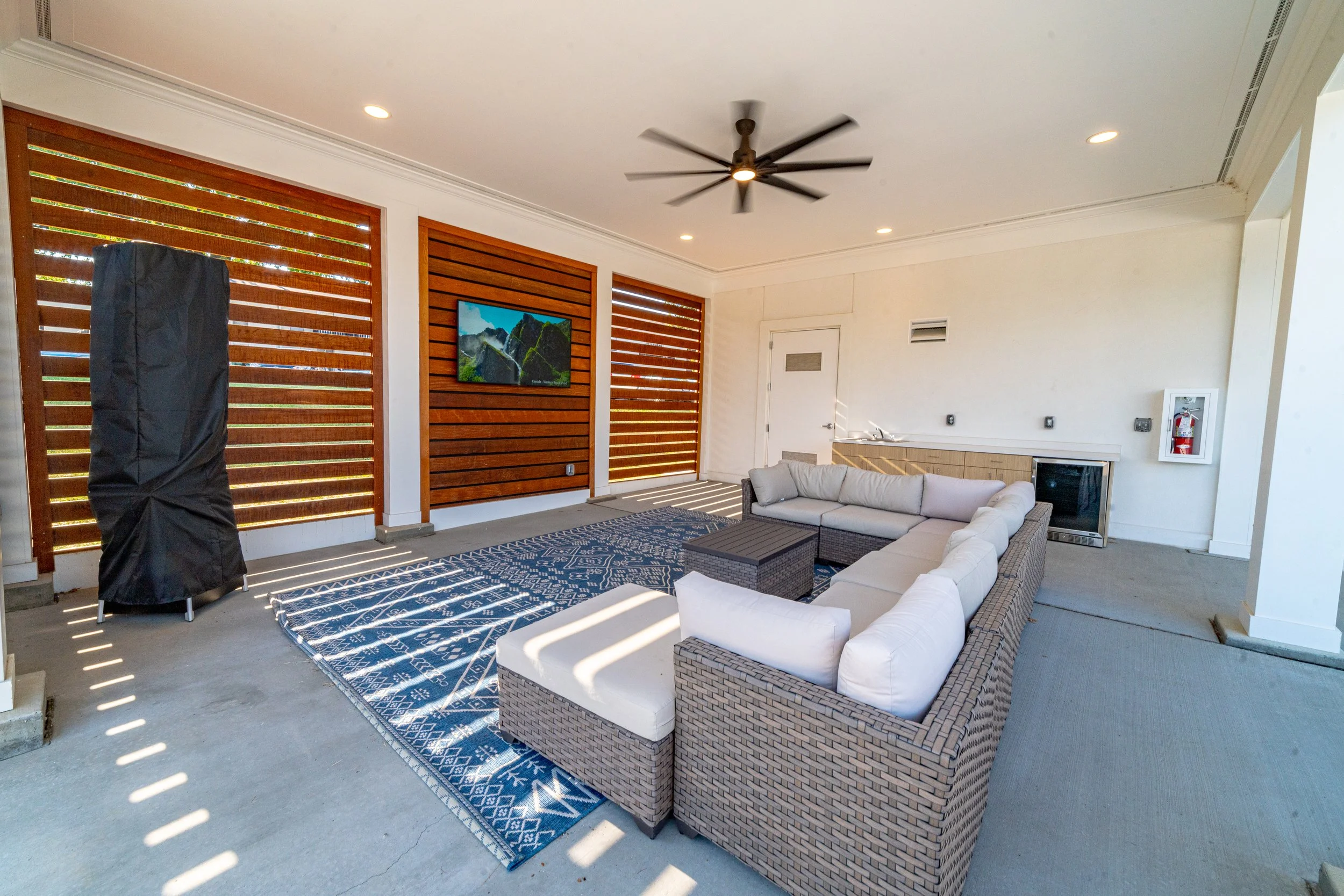 Outdoor lounge seats on pool deck with tv.
