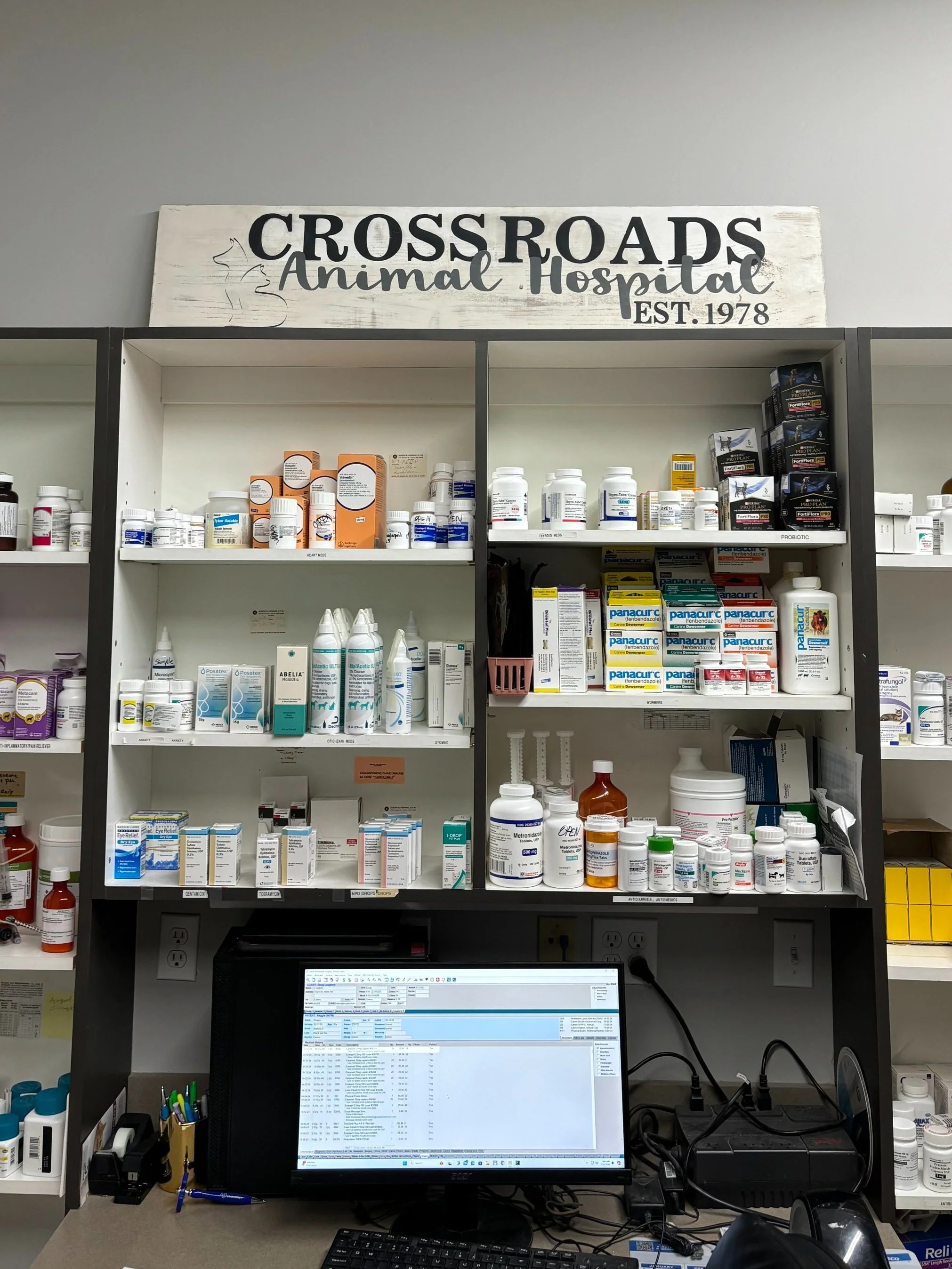 Veterinary clinic shelves with medications and computer workstation.