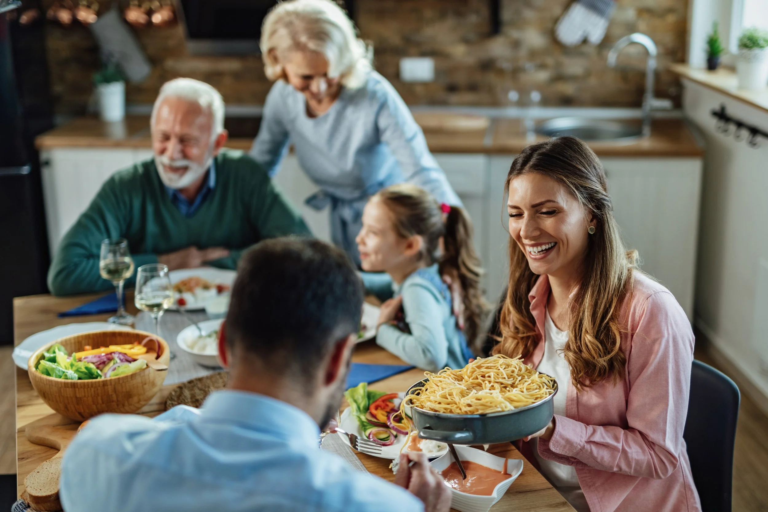 young-happy-woman-laughing-while-passing-food-her-husband-enjoying-family-lunch-dining-table.jpg
