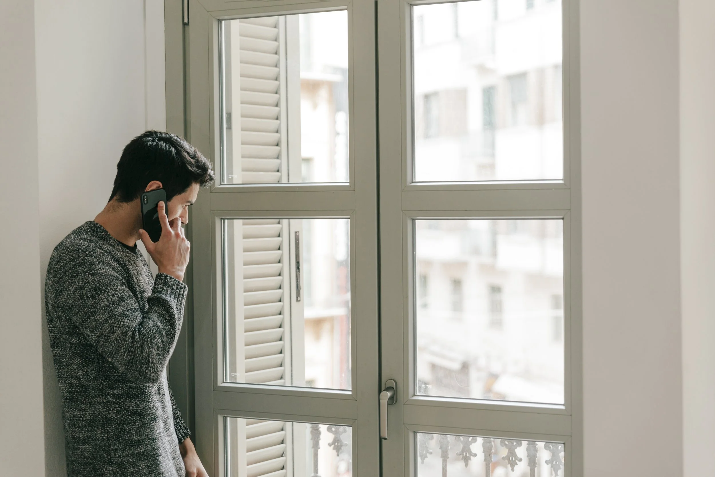 man-speaking-phone-near-window.jpg