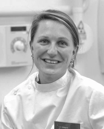 A woman with short hair smiling and wearing a lab coat.